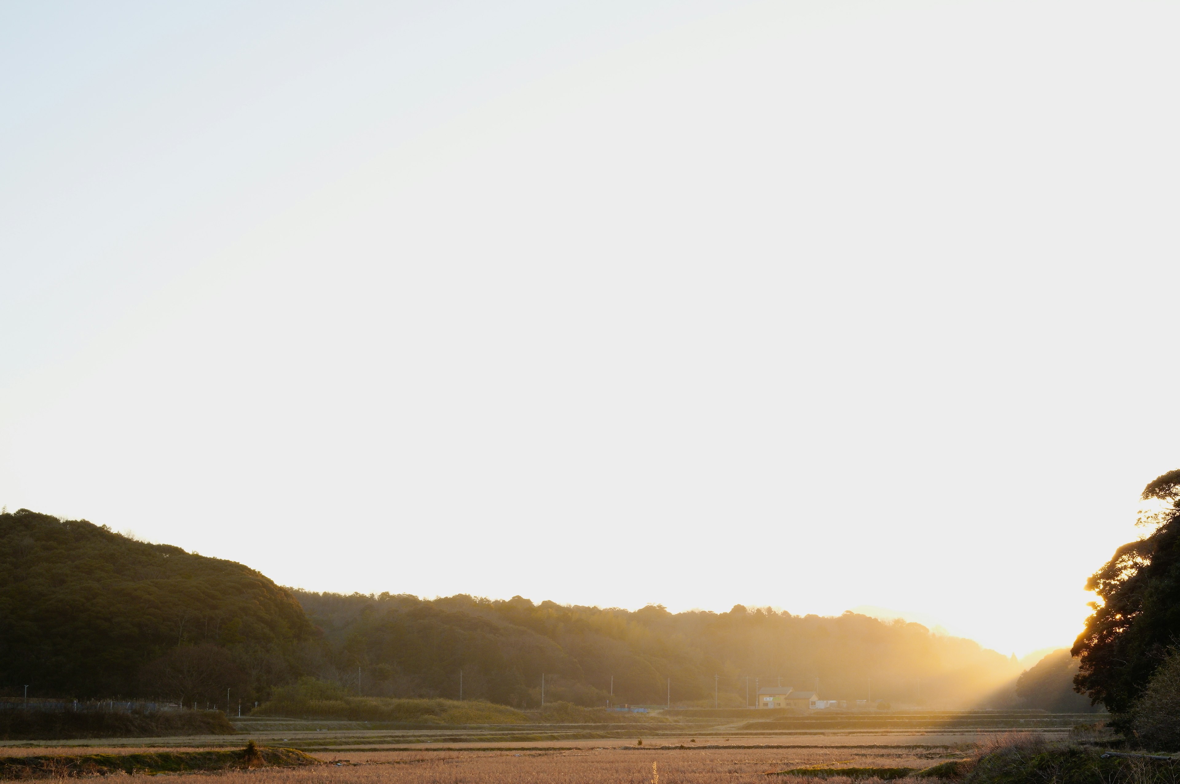 Ruhiger Sonnenuntergang, der eine Landschaft mit grünen Hügeln und weitem Himmel beleuchtet