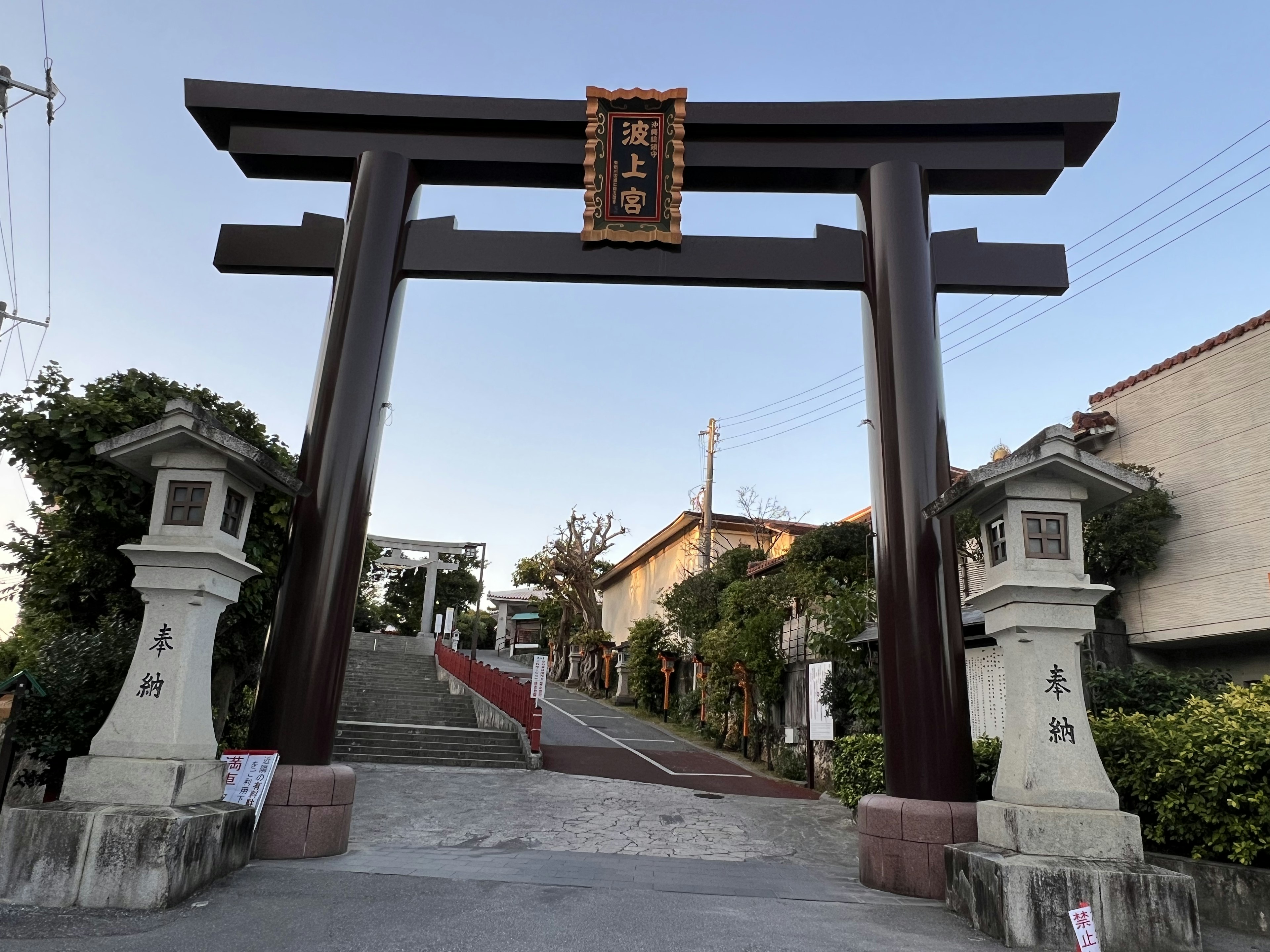 Un grande porta torii con lanterne di pietra ai lati che segna l'ingresso di un santuario giapponese