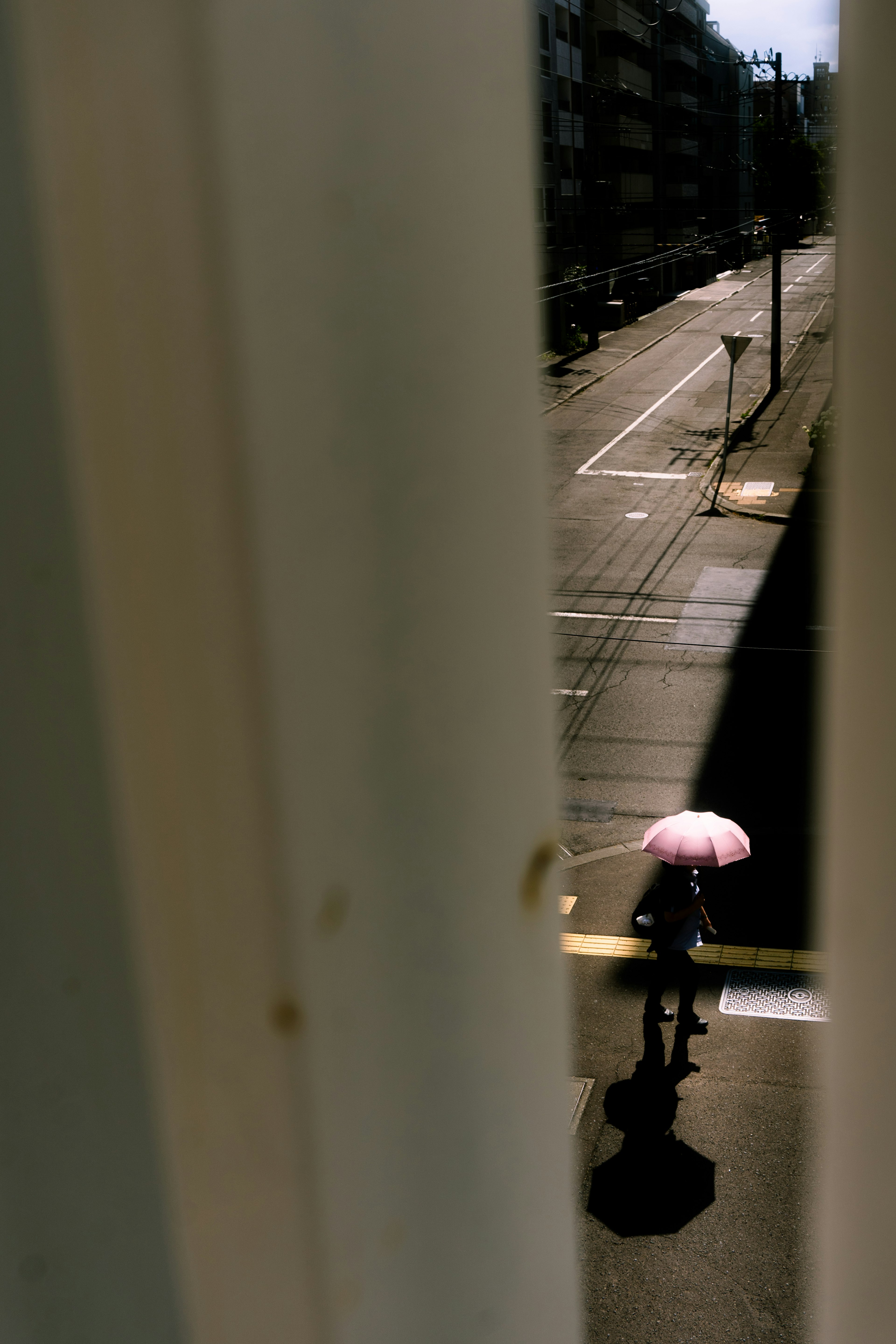 透过窗户看到的街道和一个拿着粉色雨伞的人影