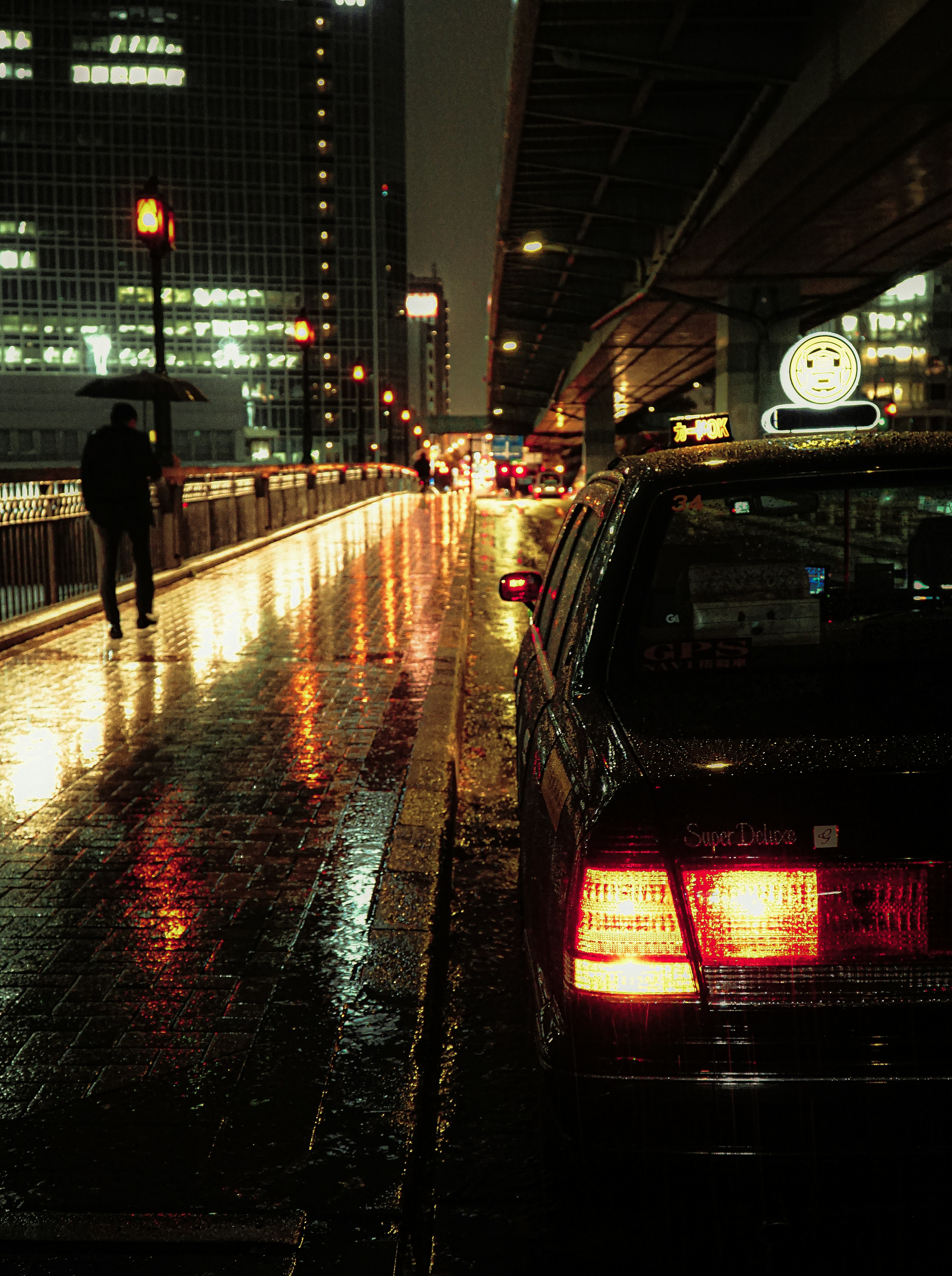 Nighttime city scene with rain-soaked pavement and illuminated taxi