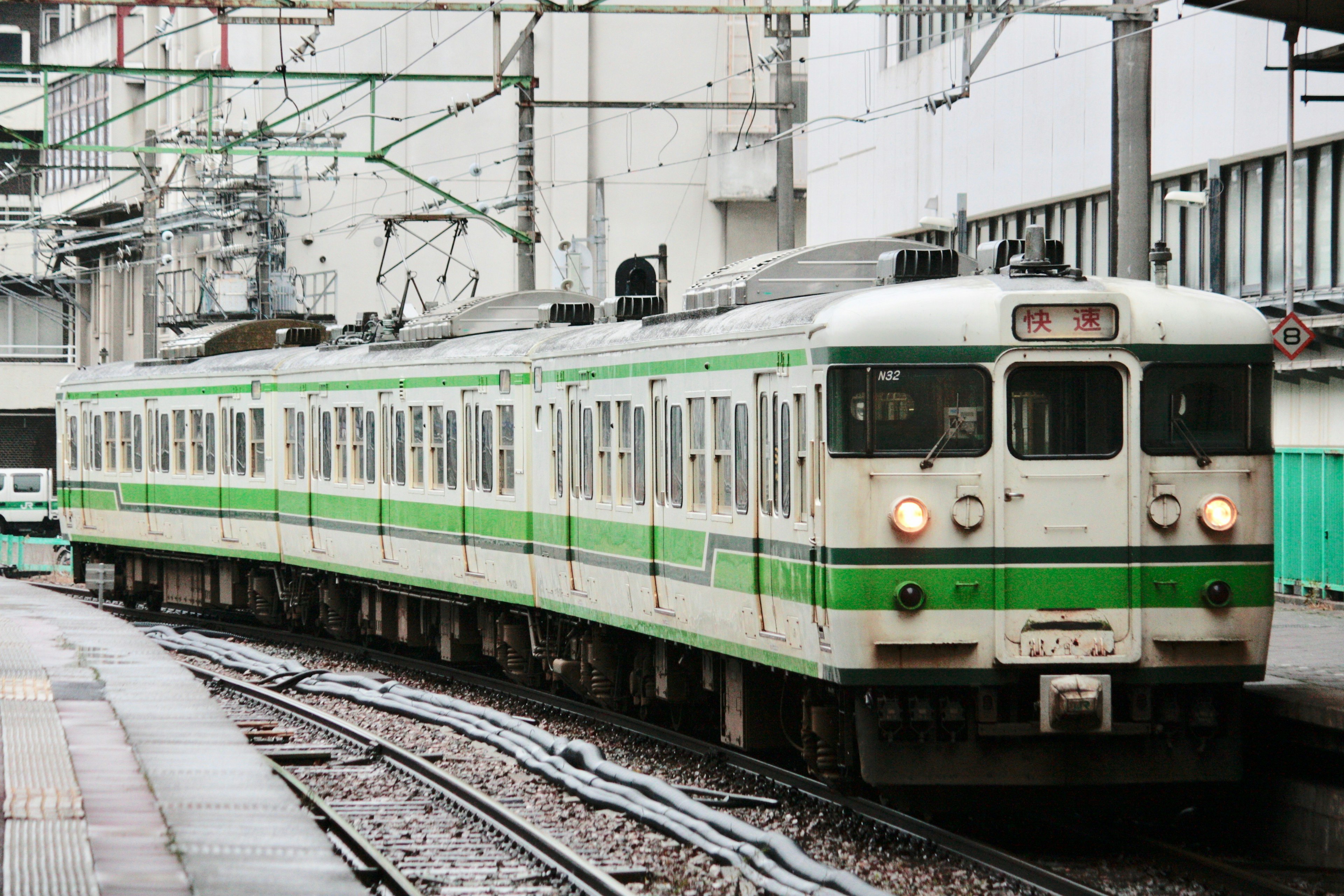 緑のストライプが特徴的な日本の電車が駅に停車中