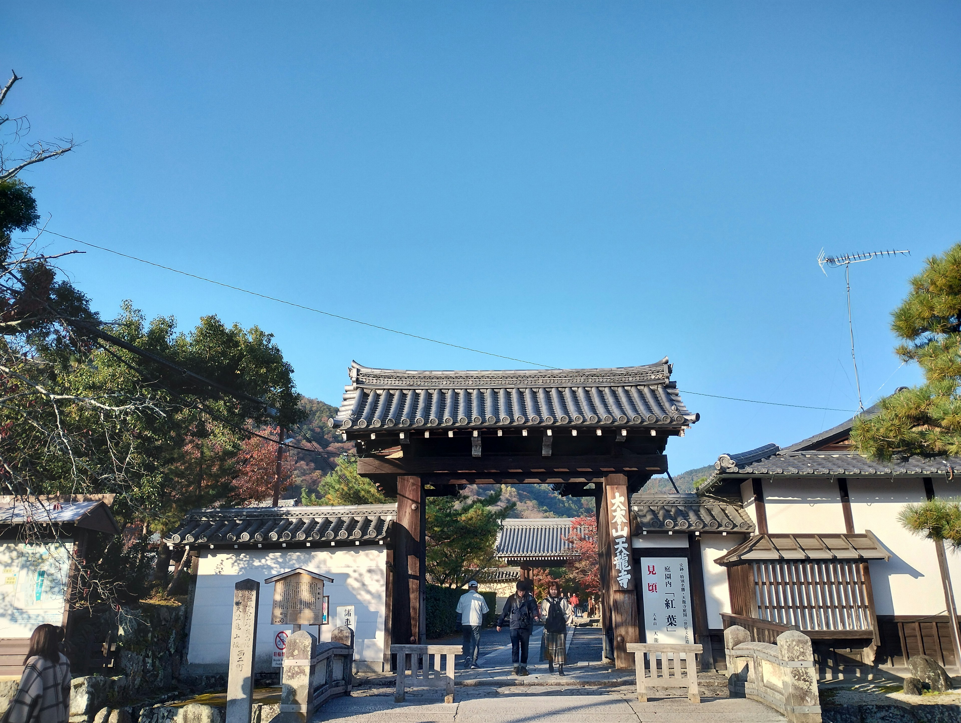 Traditional Japanese gate under a clear blue sky with surrounding buildings