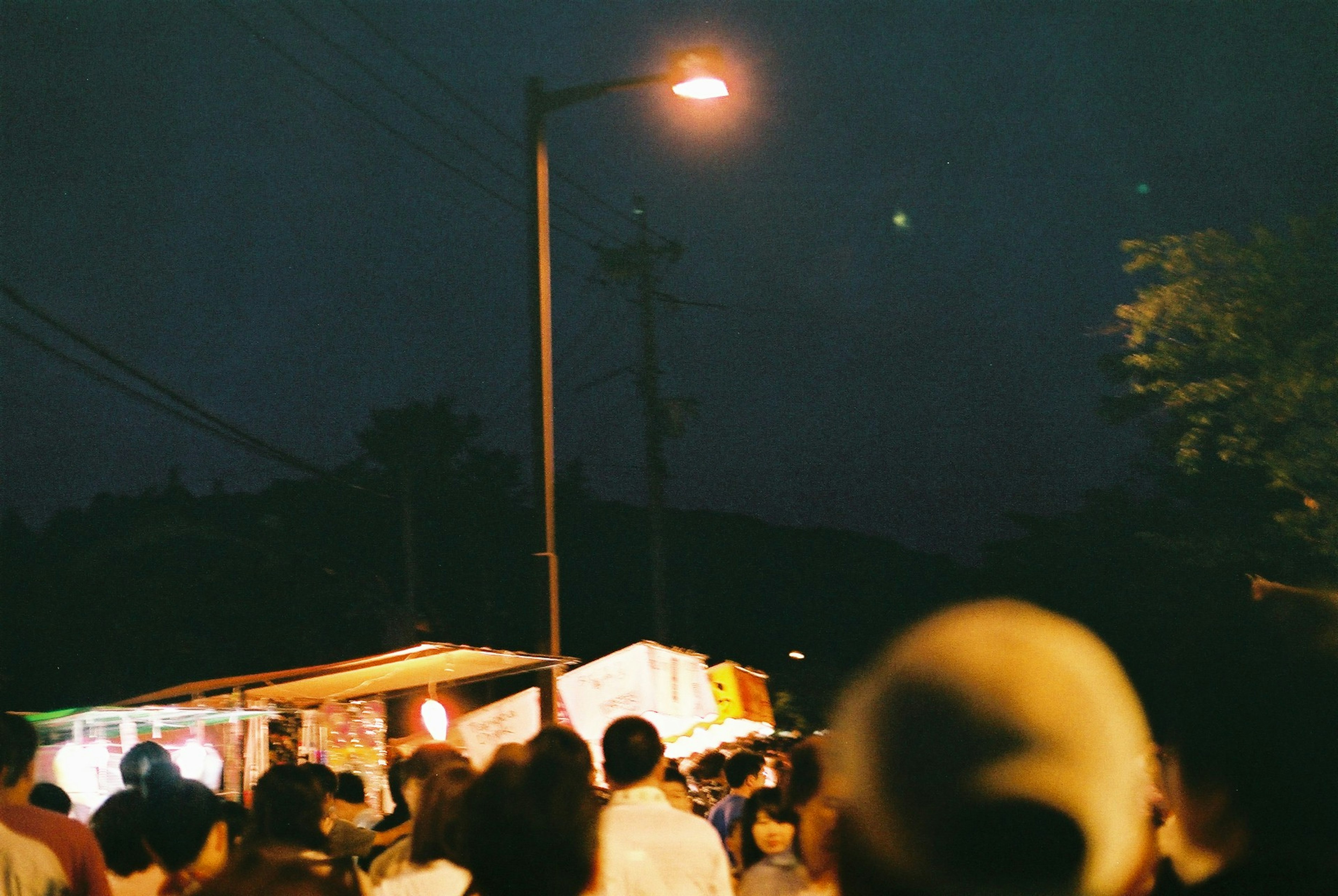 Escena de mercado nocturno con gente y luces de calle