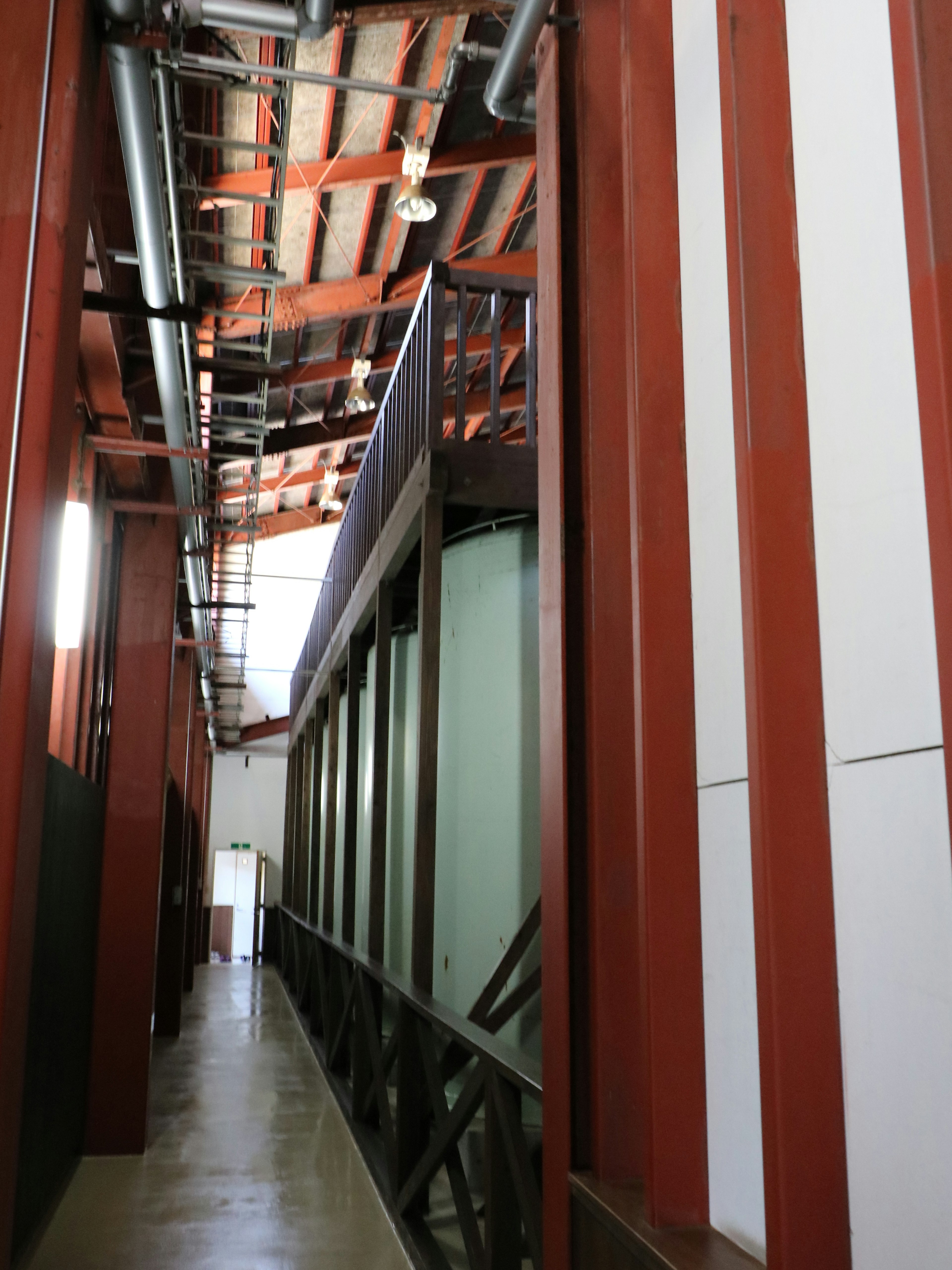 Corridor featuring red and white striped walls and exposed ceiling pipes