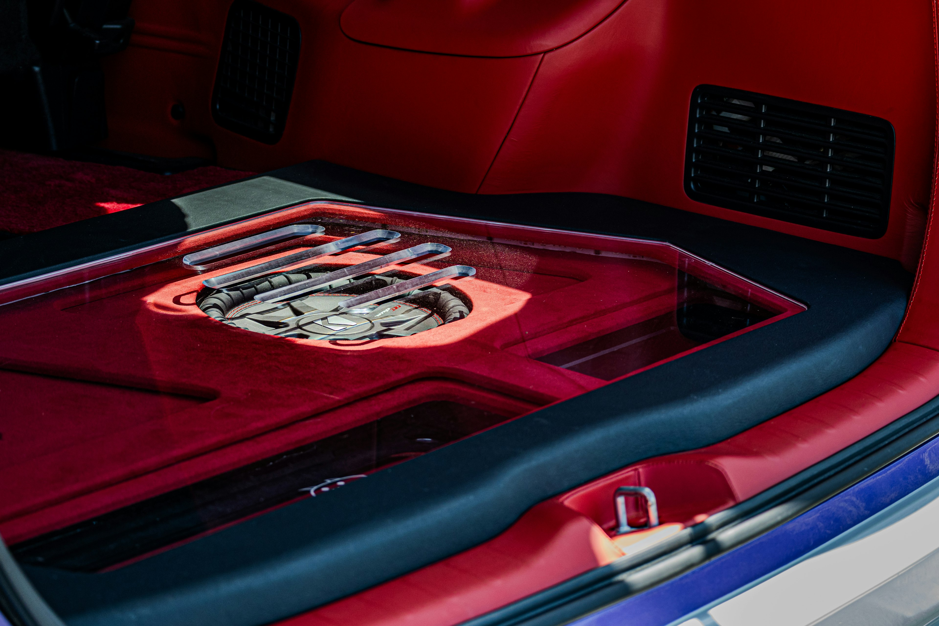 Transparent subwoofer mounted in a red car trunk with custom design panel