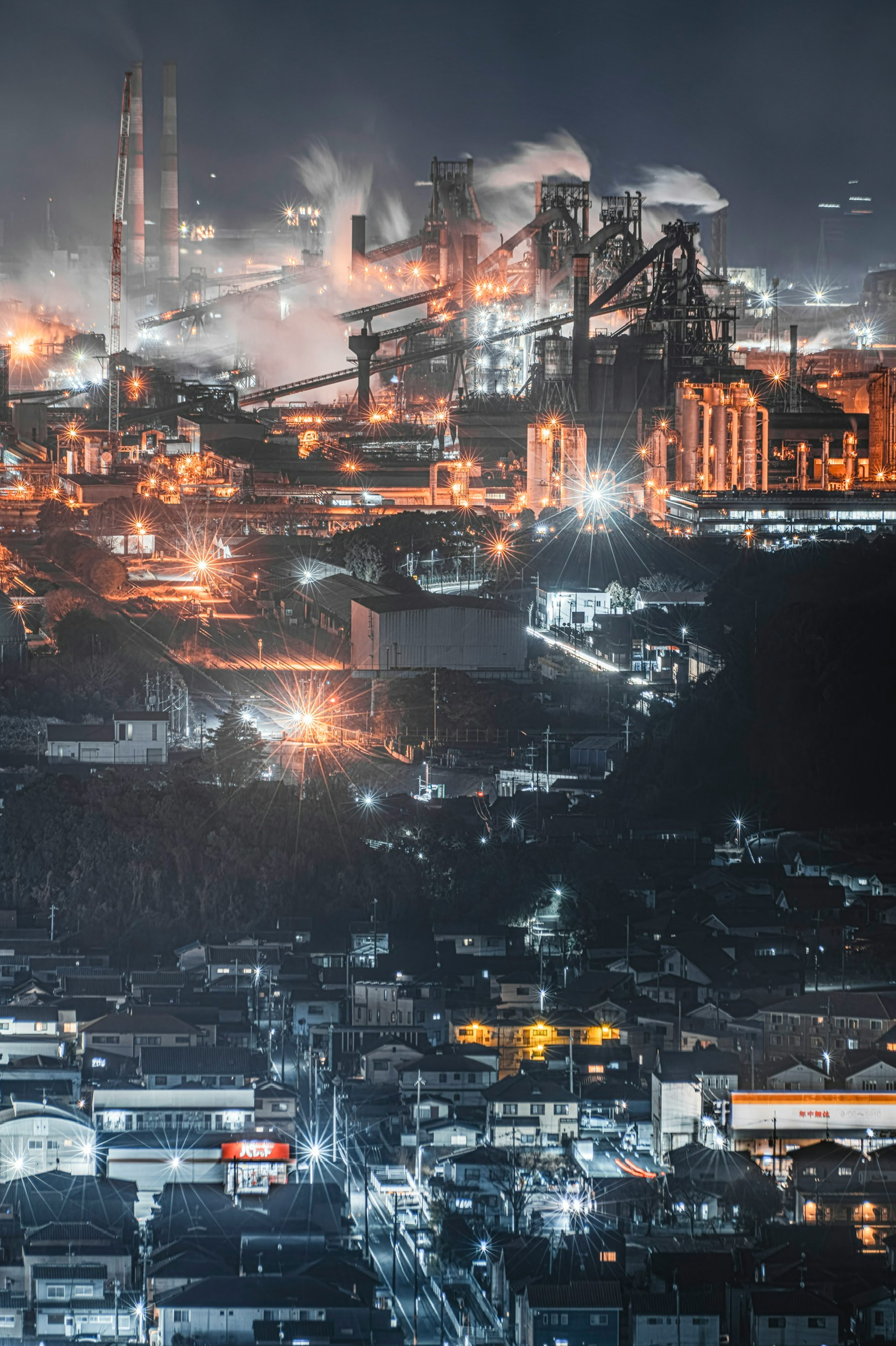 Night view of an industrial area illuminated by bright lights featuring factories and smokestacks