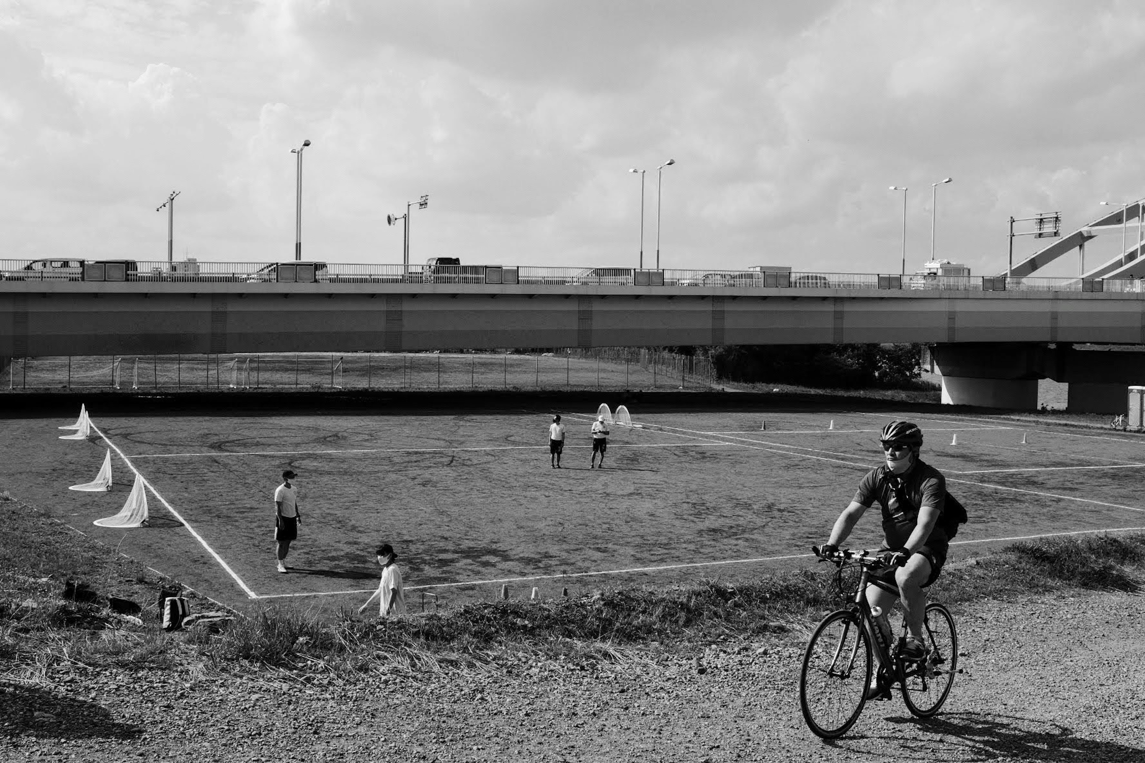 Un hombre montando una bicicleta cerca de niños jugando fútbol en un campo