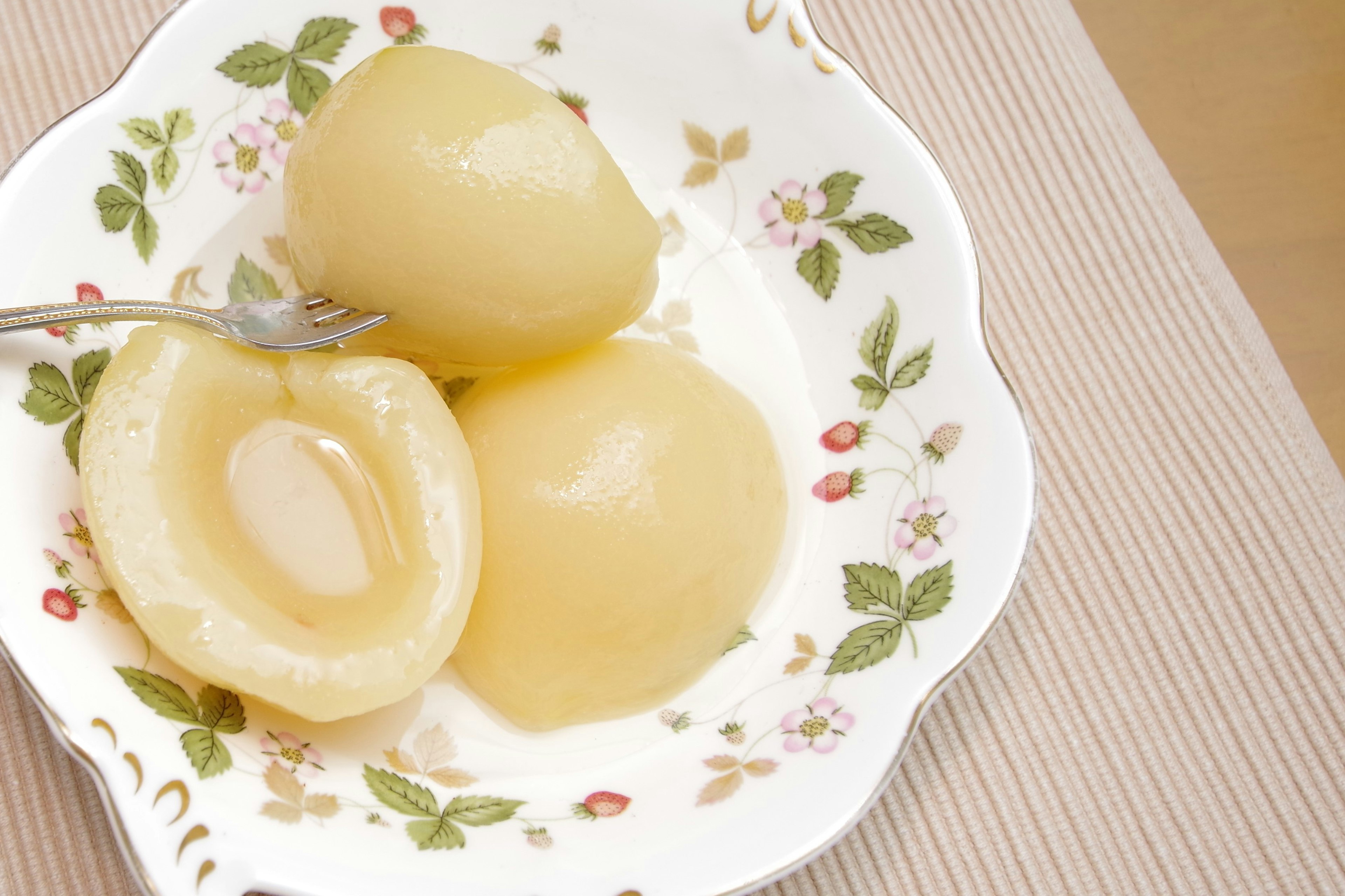 Tranches de pêches en conserve sucrées servies sur une assiette blanche à fleurs