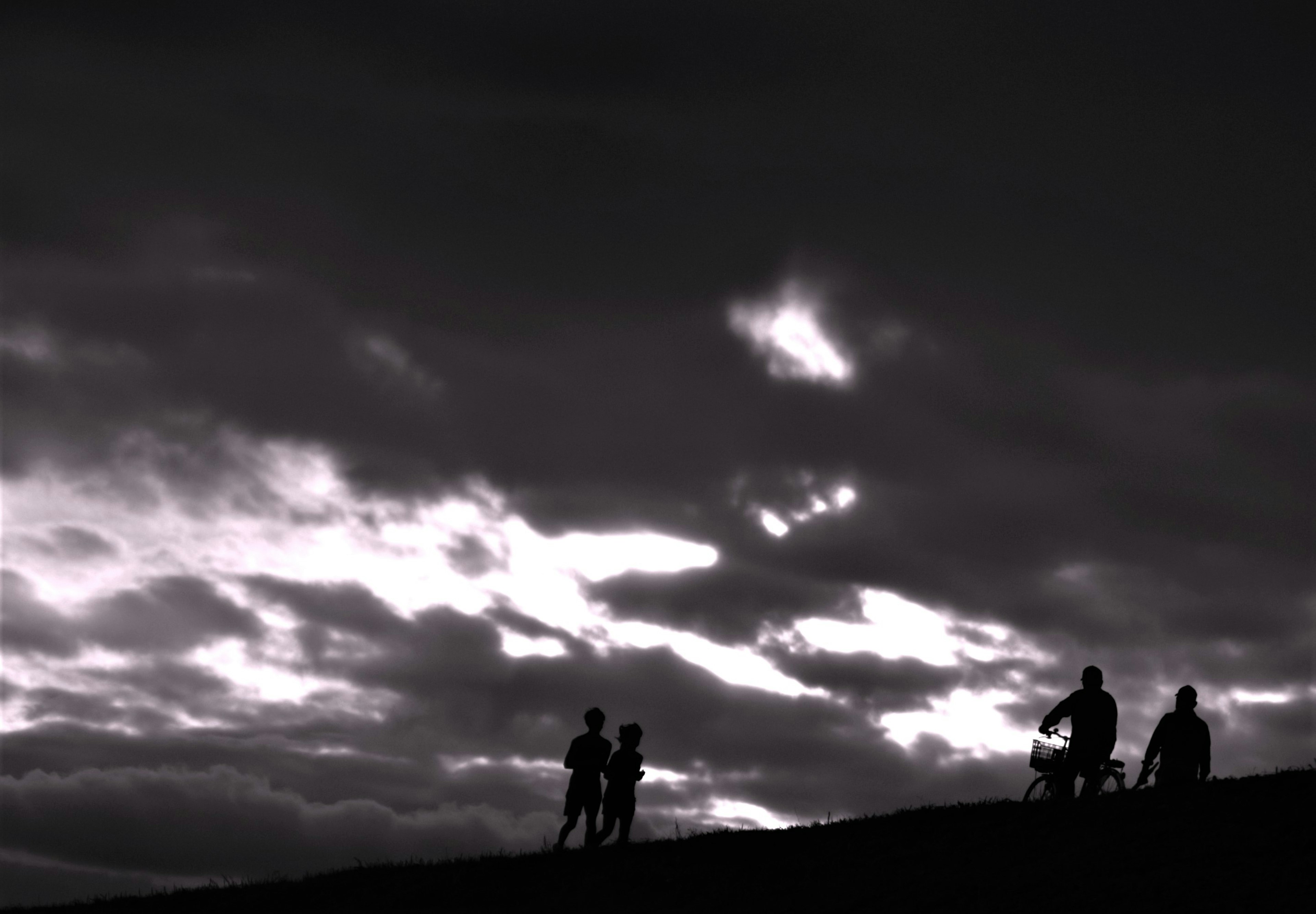 Silhouetten von Personen vor einem dunklen Himmel