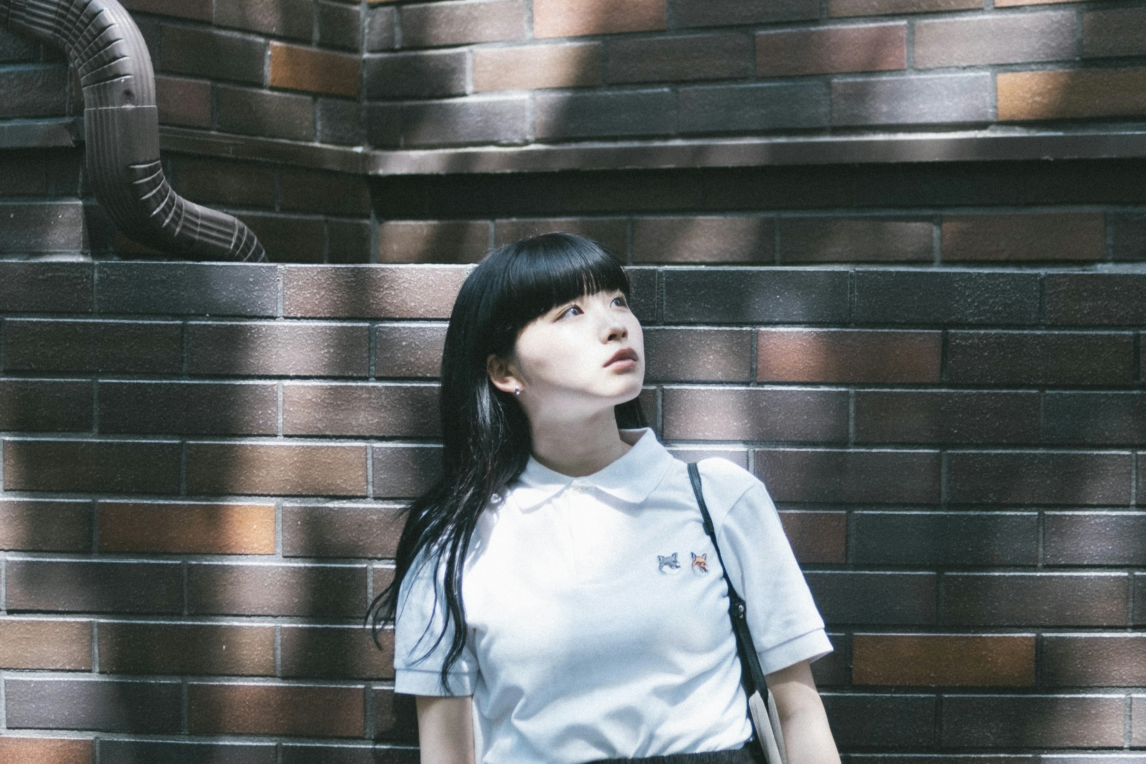 Portrait of a woman looking up against a brick wall