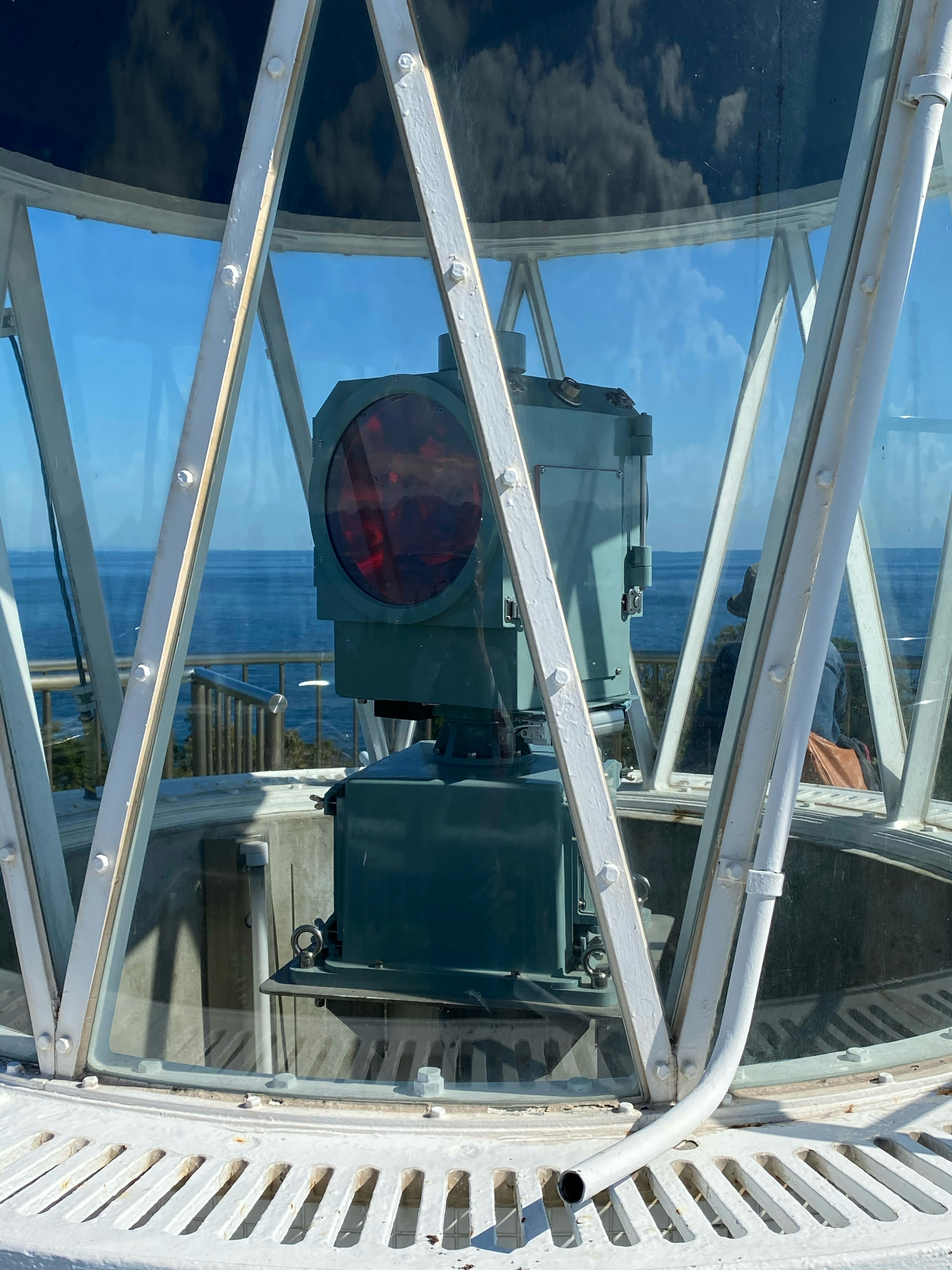 Interior view of a lighthouse featuring a red light against a blue ocean backdrop