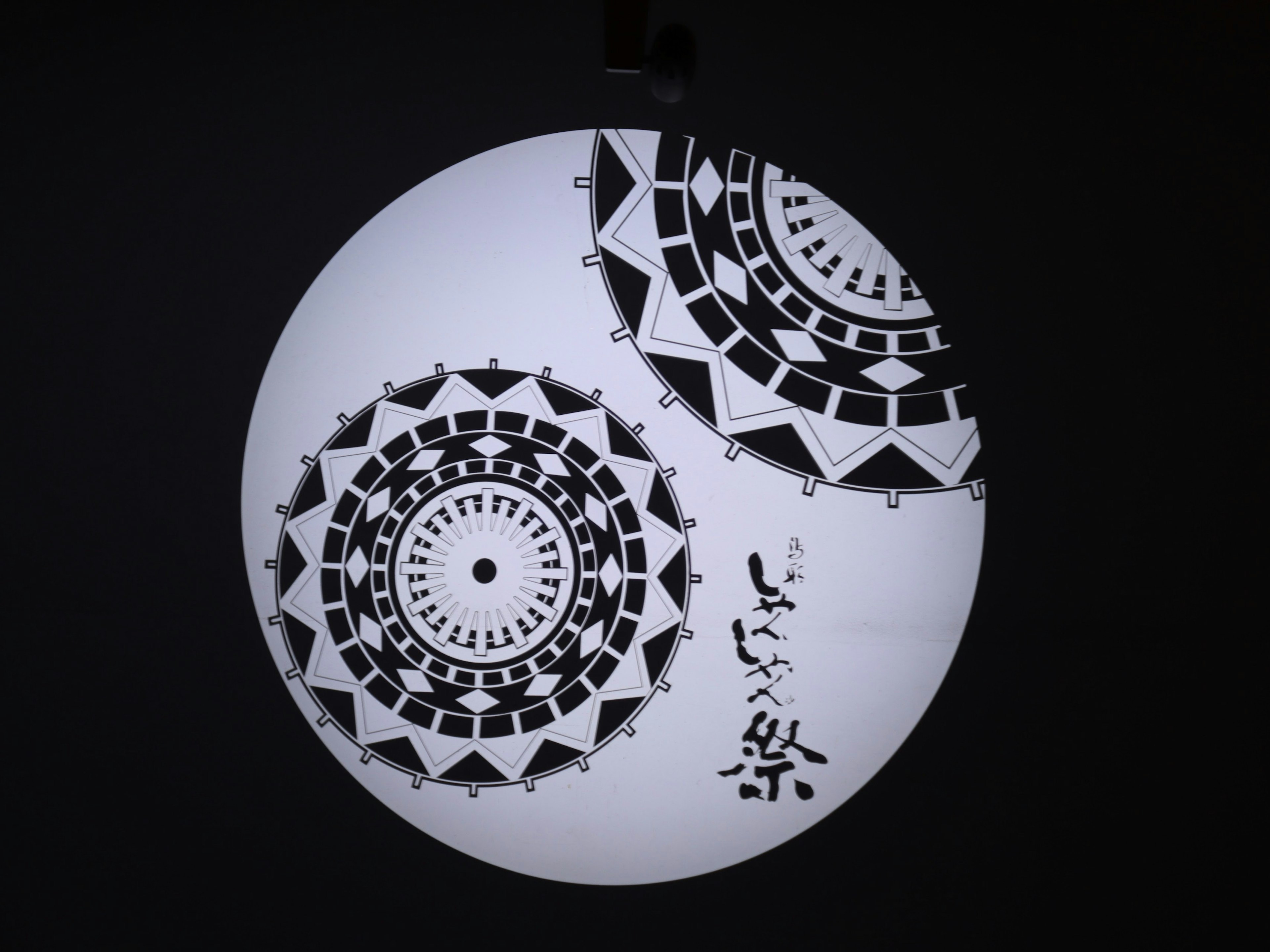 Circular black and white art featuring geometric patterns and Japanese text