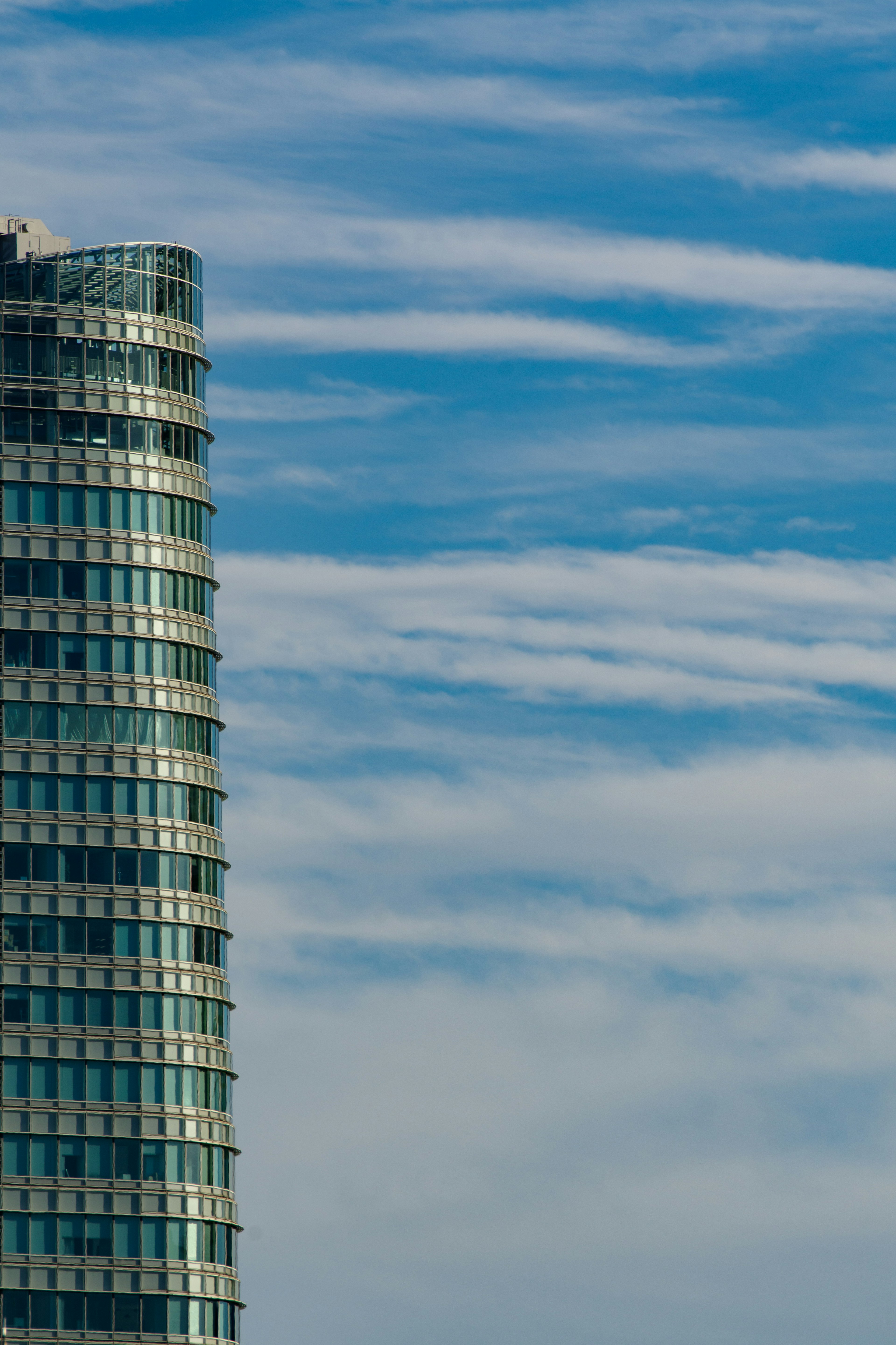 Glass skyscraper towering under a blue sky