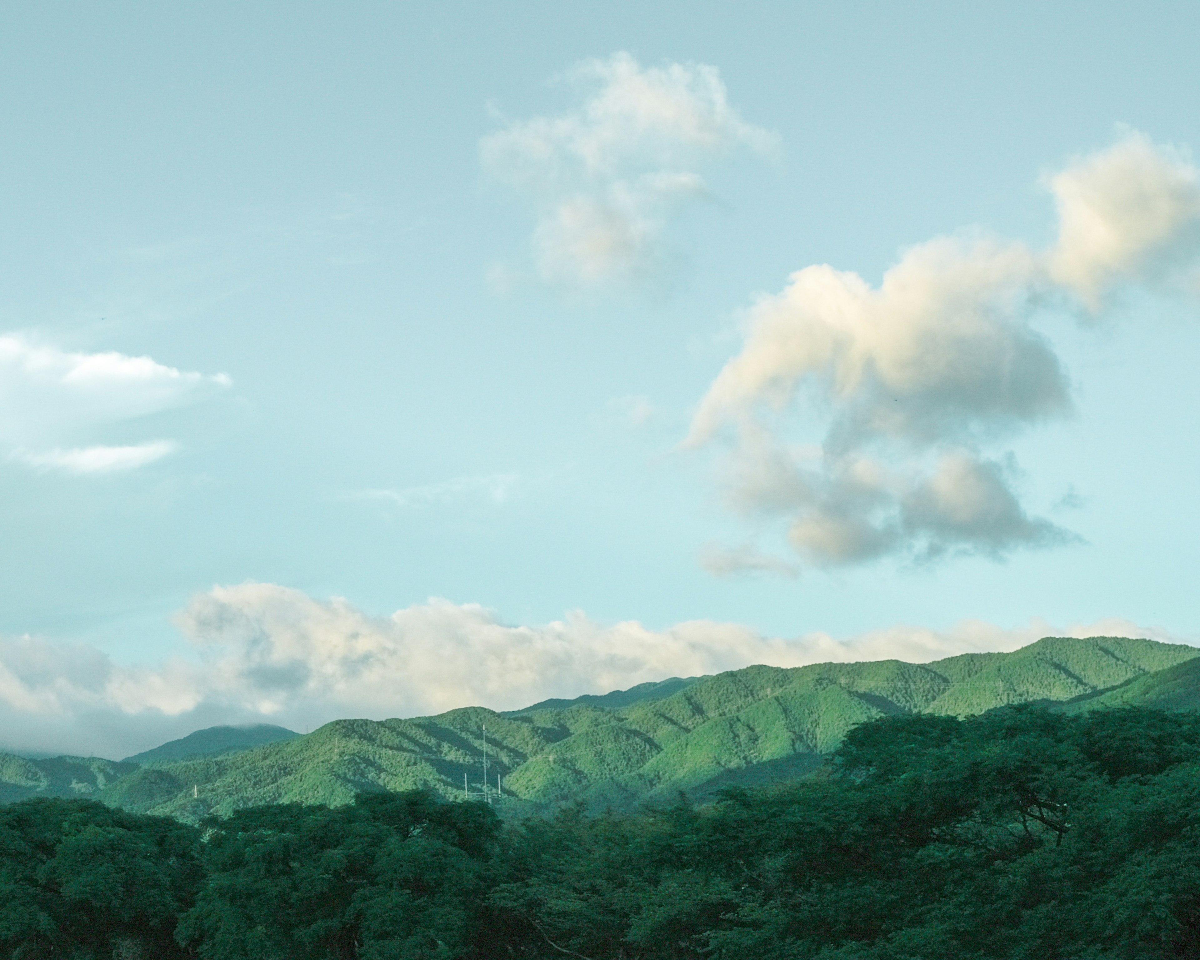 Gunung hijau subur di bawah langit biru yang cerah