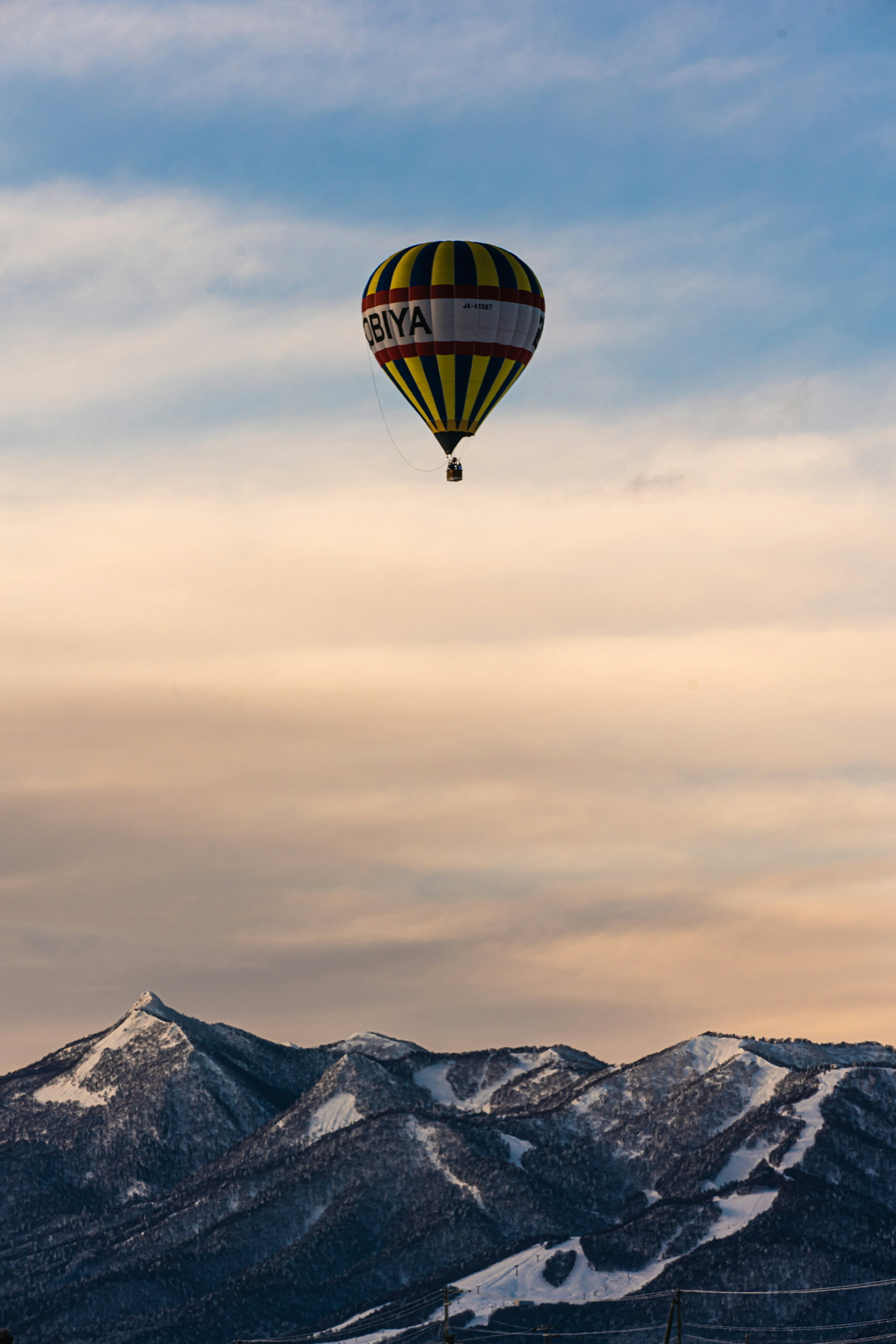 Colorato pallone aerostatico che fluttua sopra montagne innevate