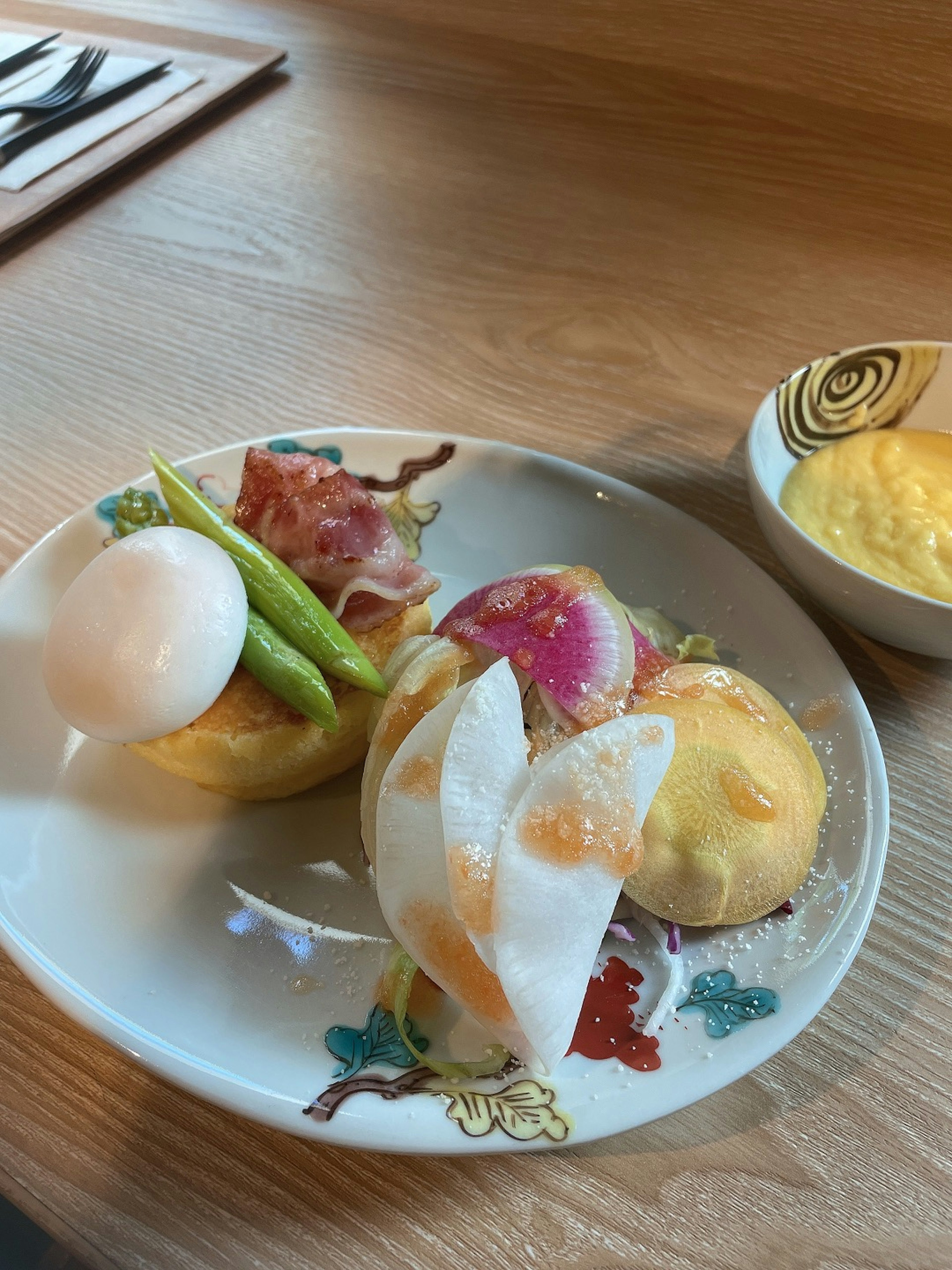 A colorful plate featuring a boiled egg, ham, green beans, vibrant vegetables, and a dessert-like item