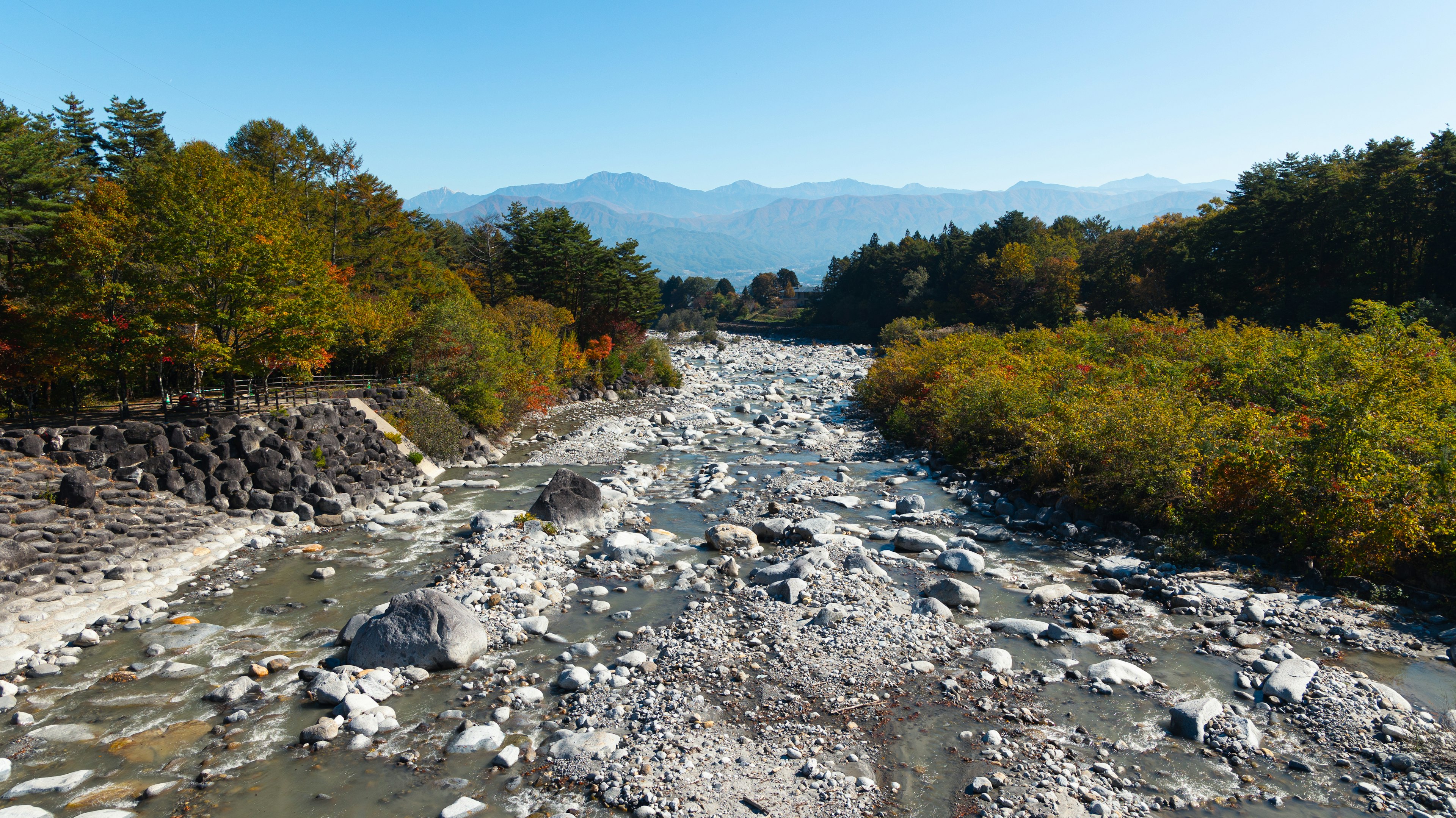 Lecho de río pintoresco con árboles coloridos y montañas distantes