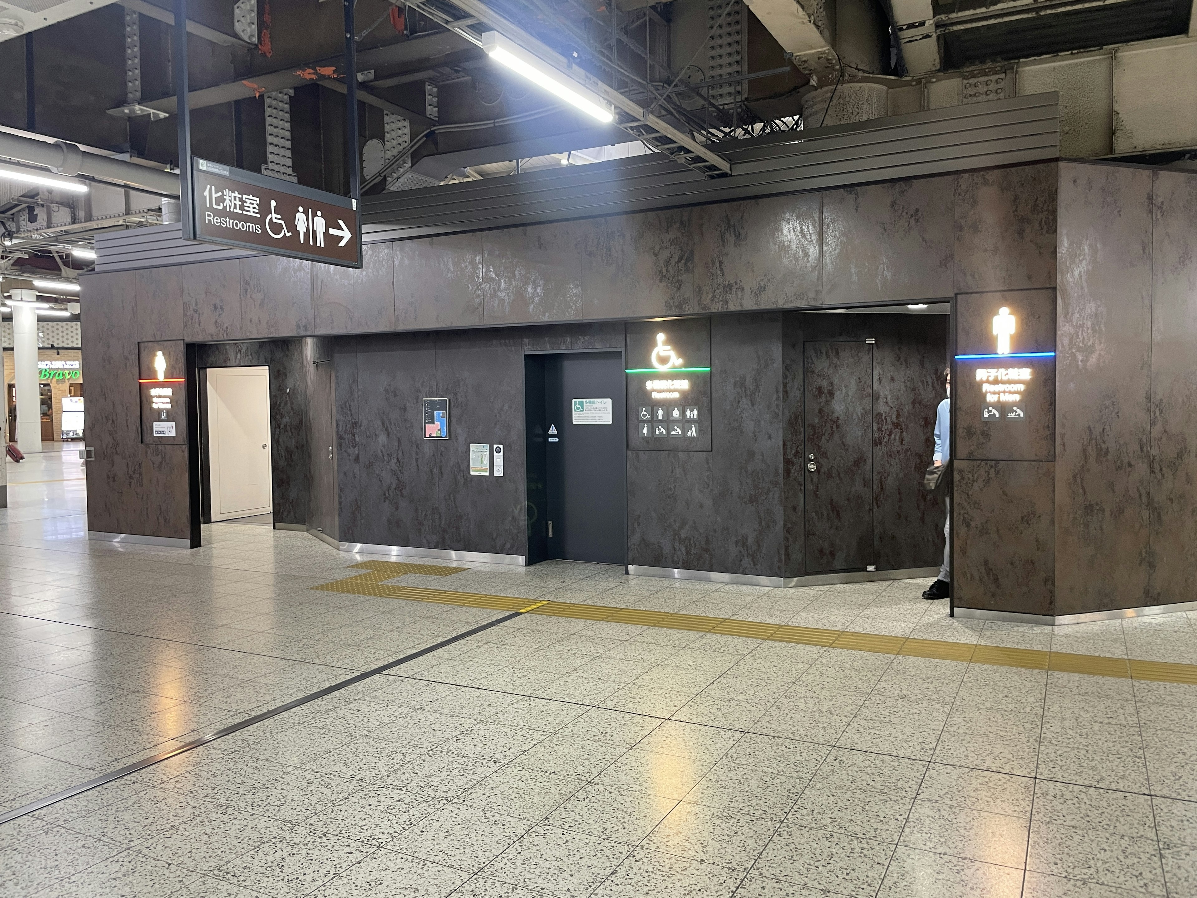 Photo of restroom entrances inside a train station featuring silver signs and black doors