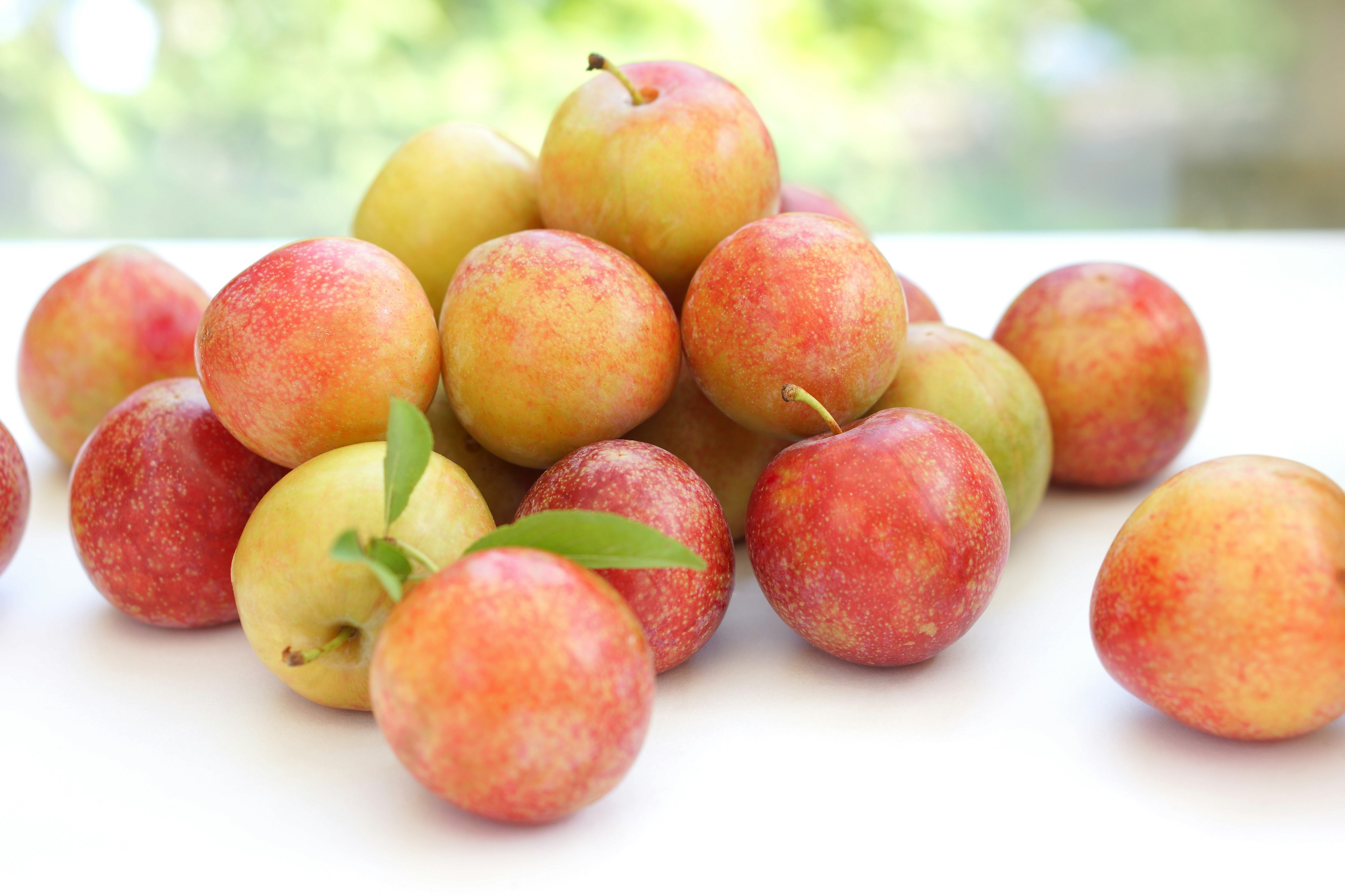 A pile of fresh red and yellow apples with a blurred green background