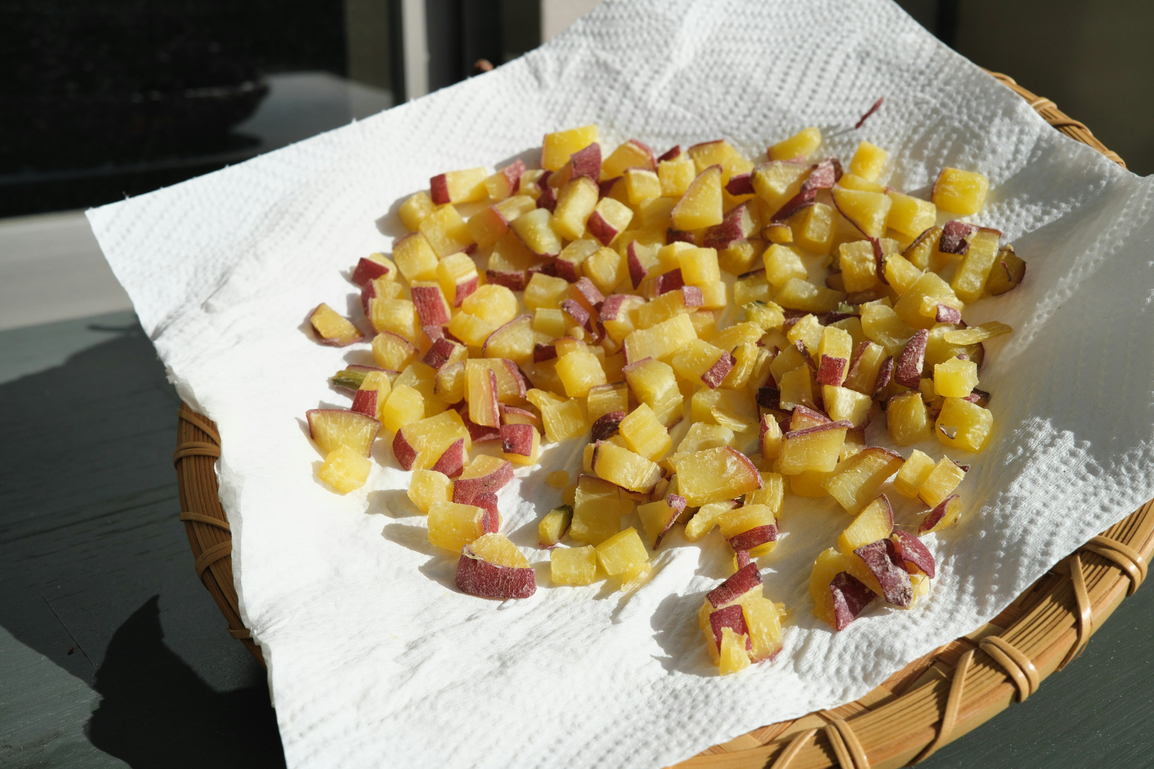 Patatas dulces amarillas en cubos dispuestas en una canasta sobre una toalla de papel