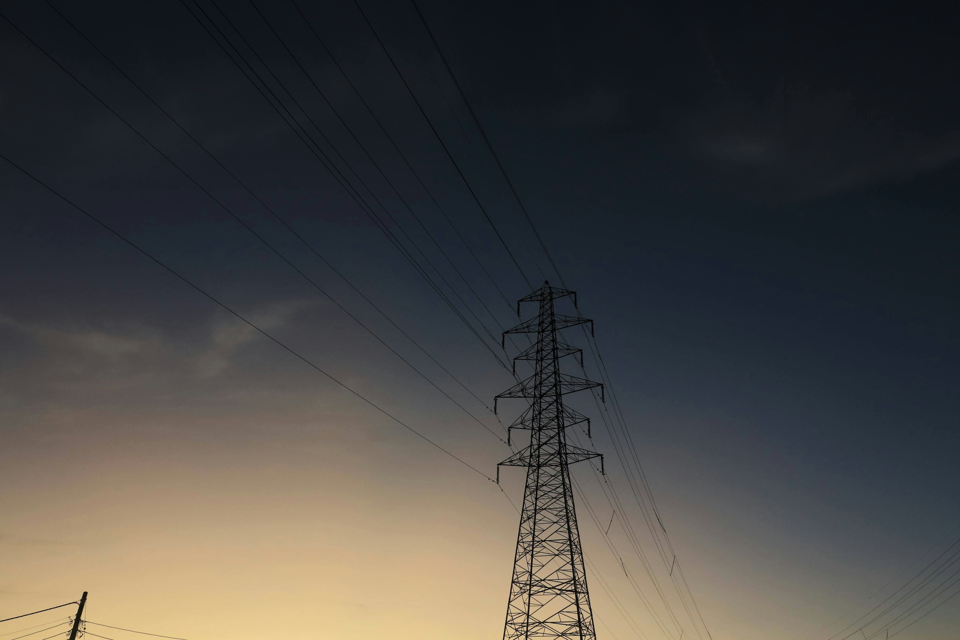 Silhouette di una torre elettrica contro un cielo sfumato al crepuscolo