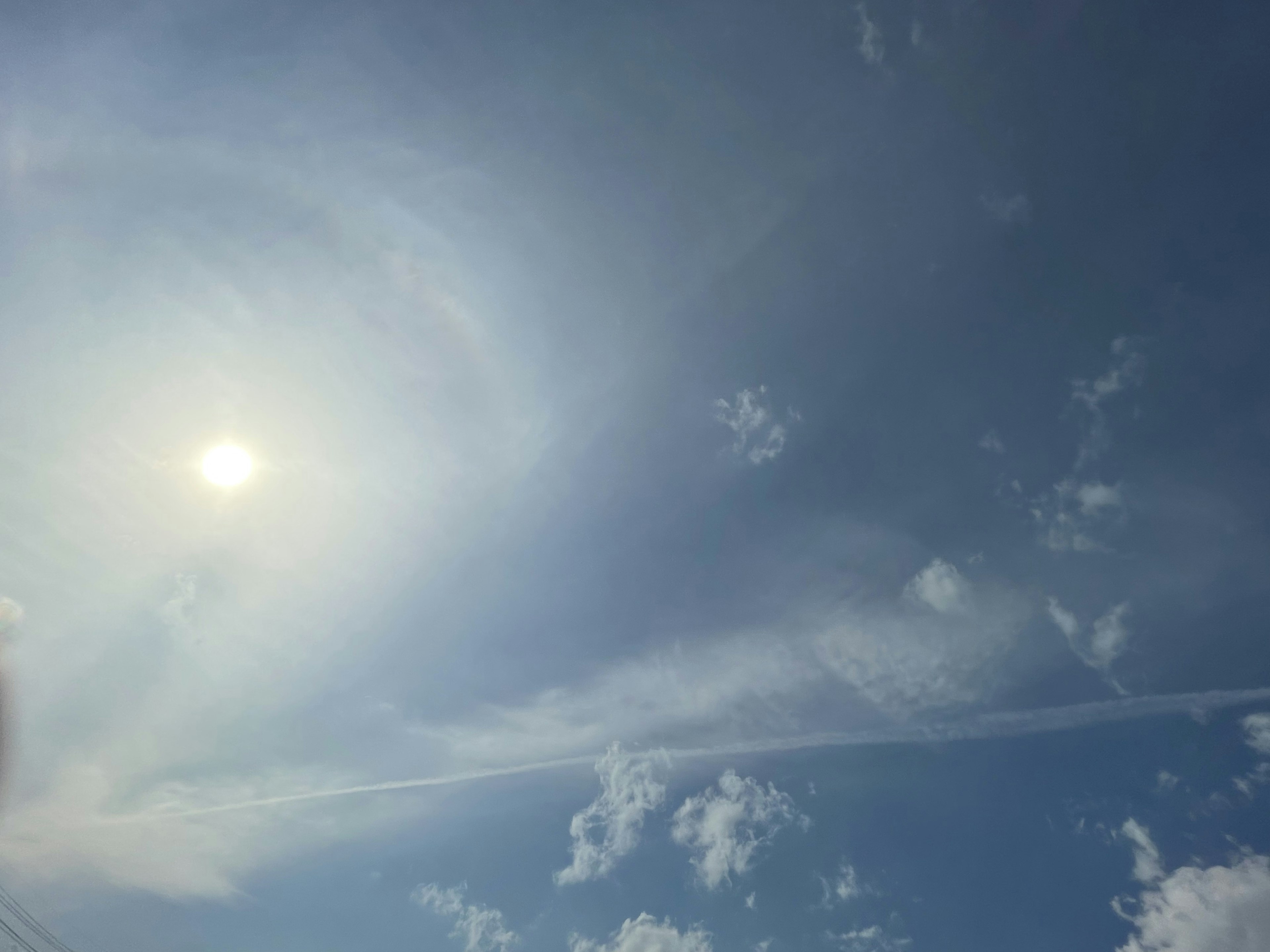 青空に太陽と白い雲が広がる風景