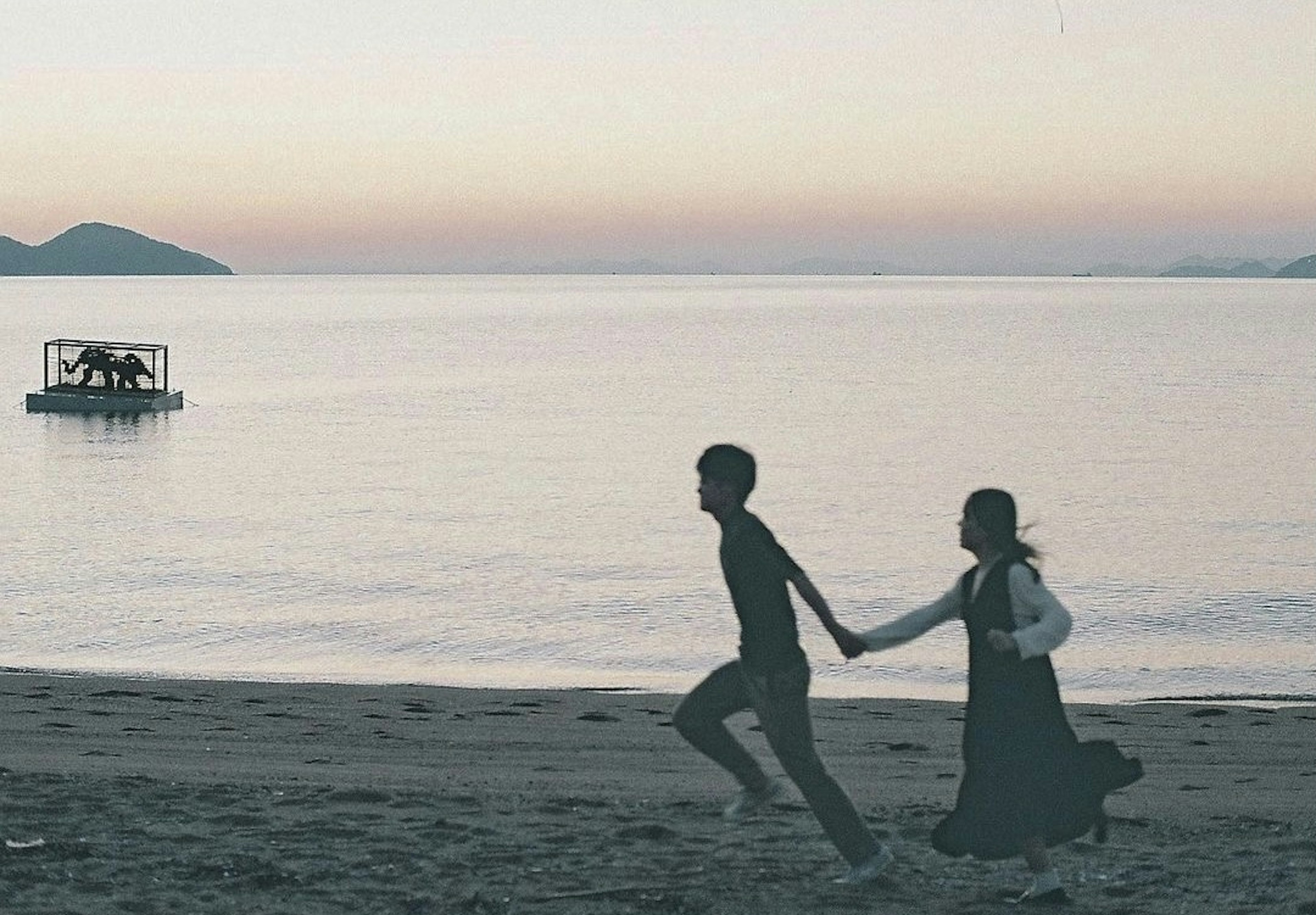 Silhouette d'un couple courant main dans la main sur la plage au coucher du soleil sur des eaux calmes