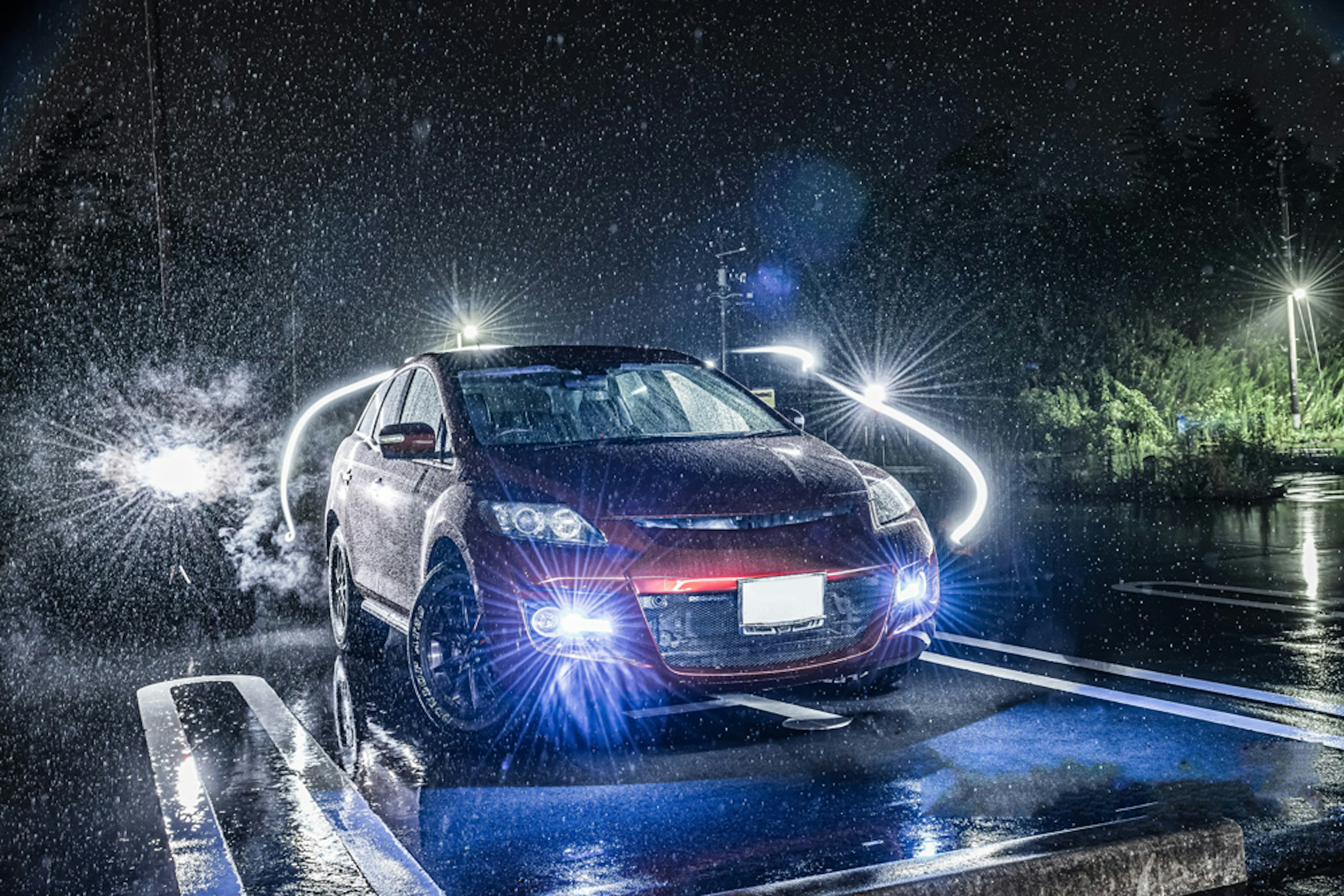 Rotes Auto beleuchtet im Regen bei Nacht