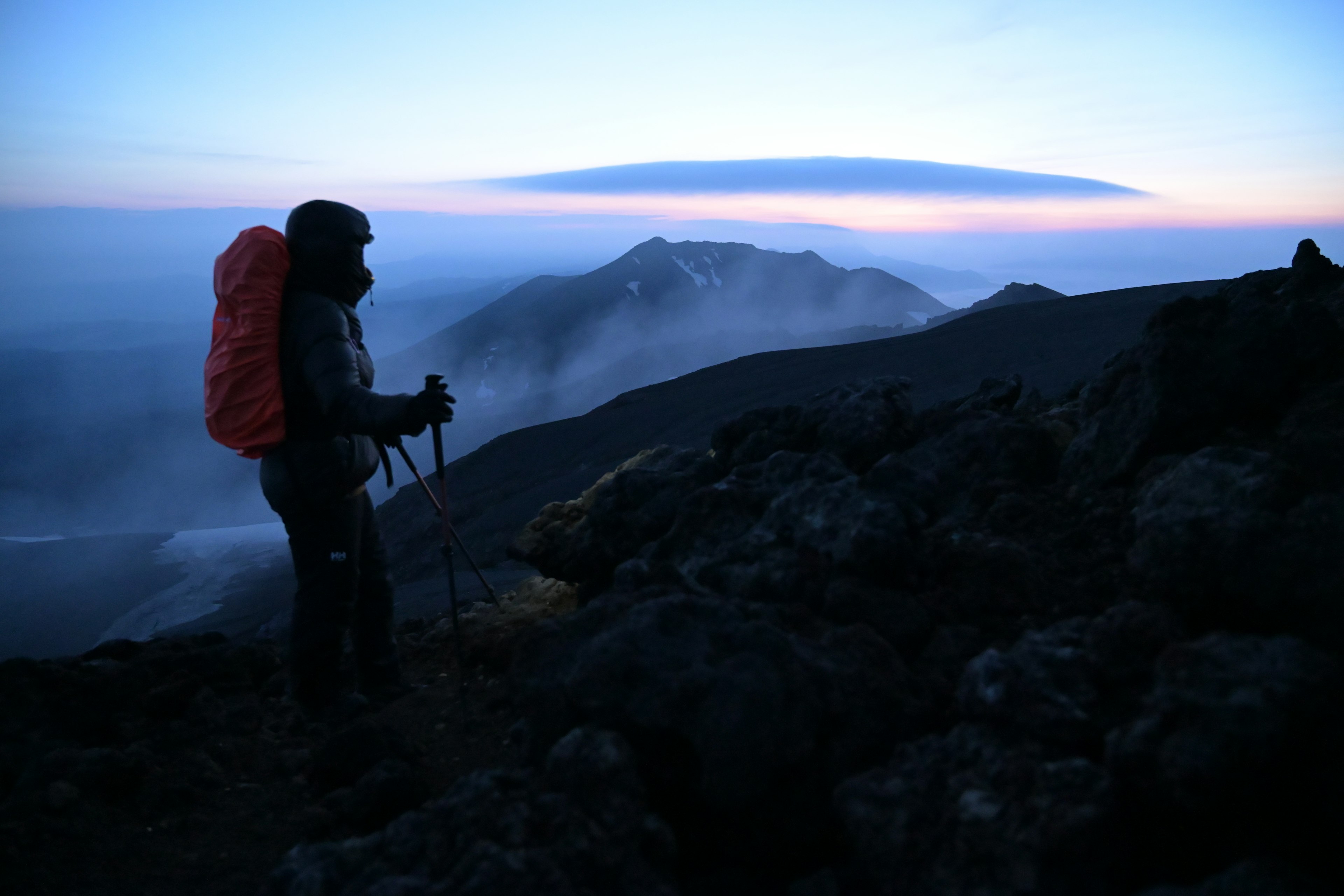 山の頂上に立つ登山者と夕暮れの空