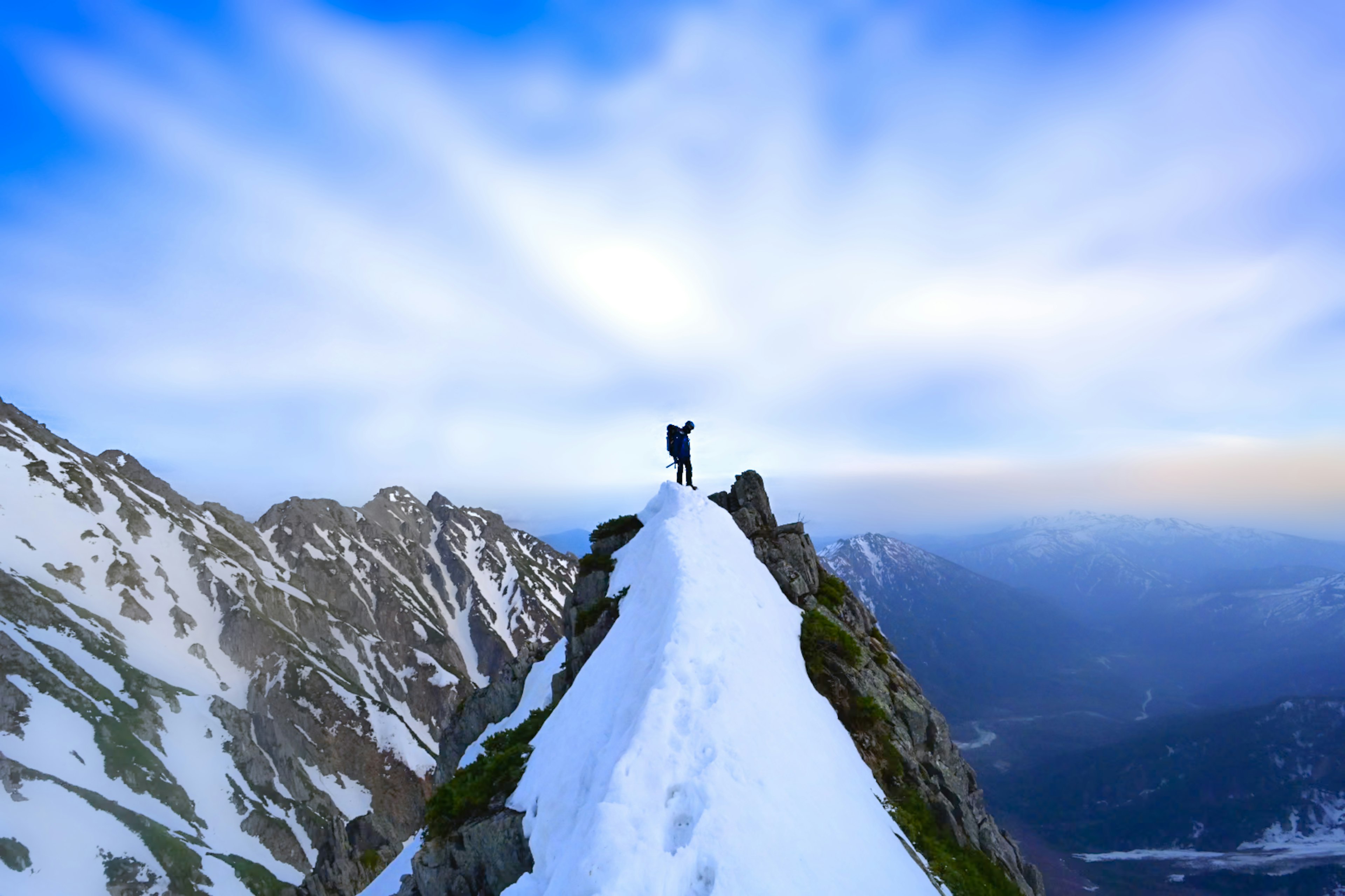 Silhouette di un alpinista in piedi su una cima innevata