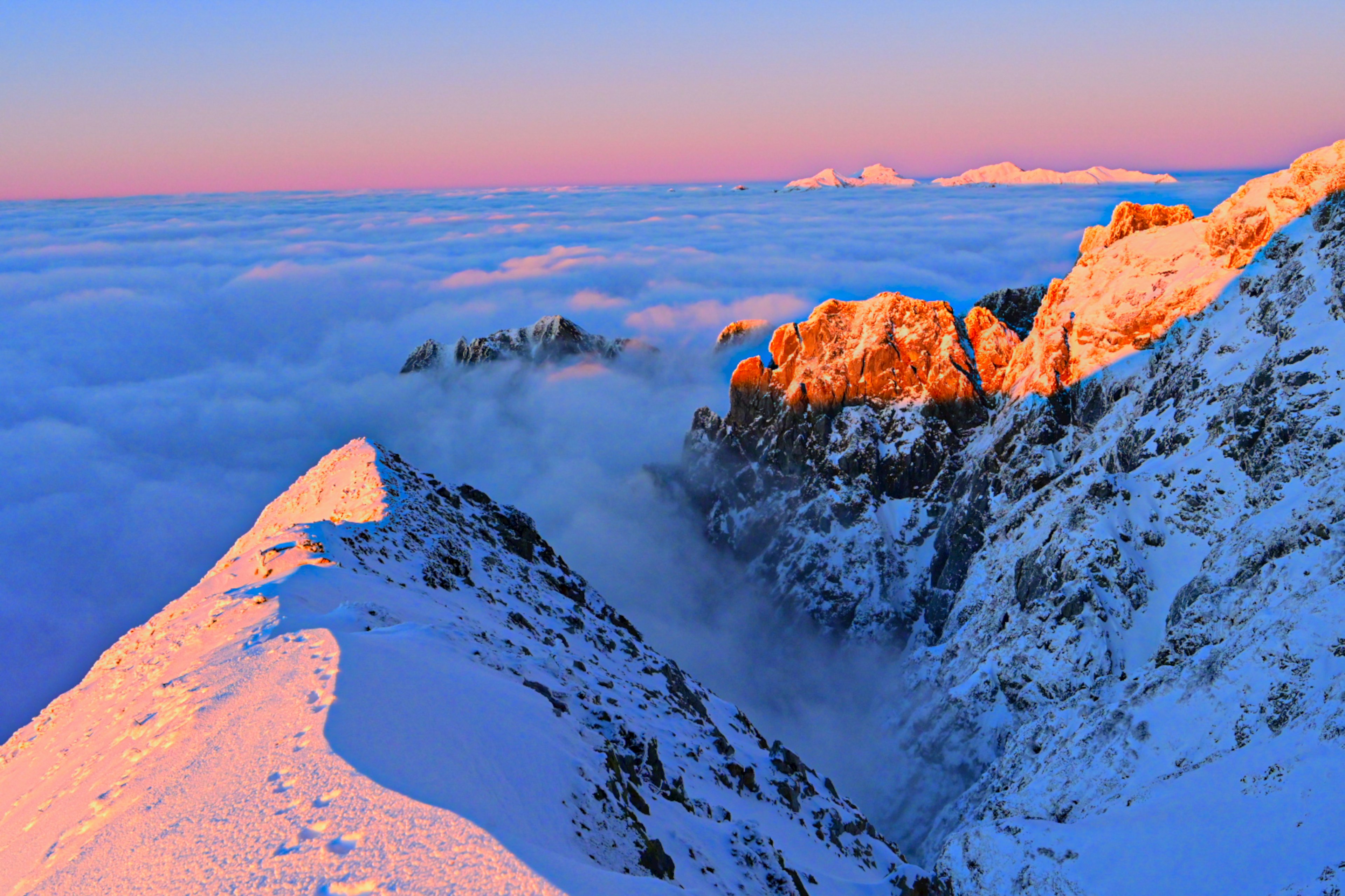 Impresionante vista del amanecer desde la cima de una montaña nevada sobre las nubes