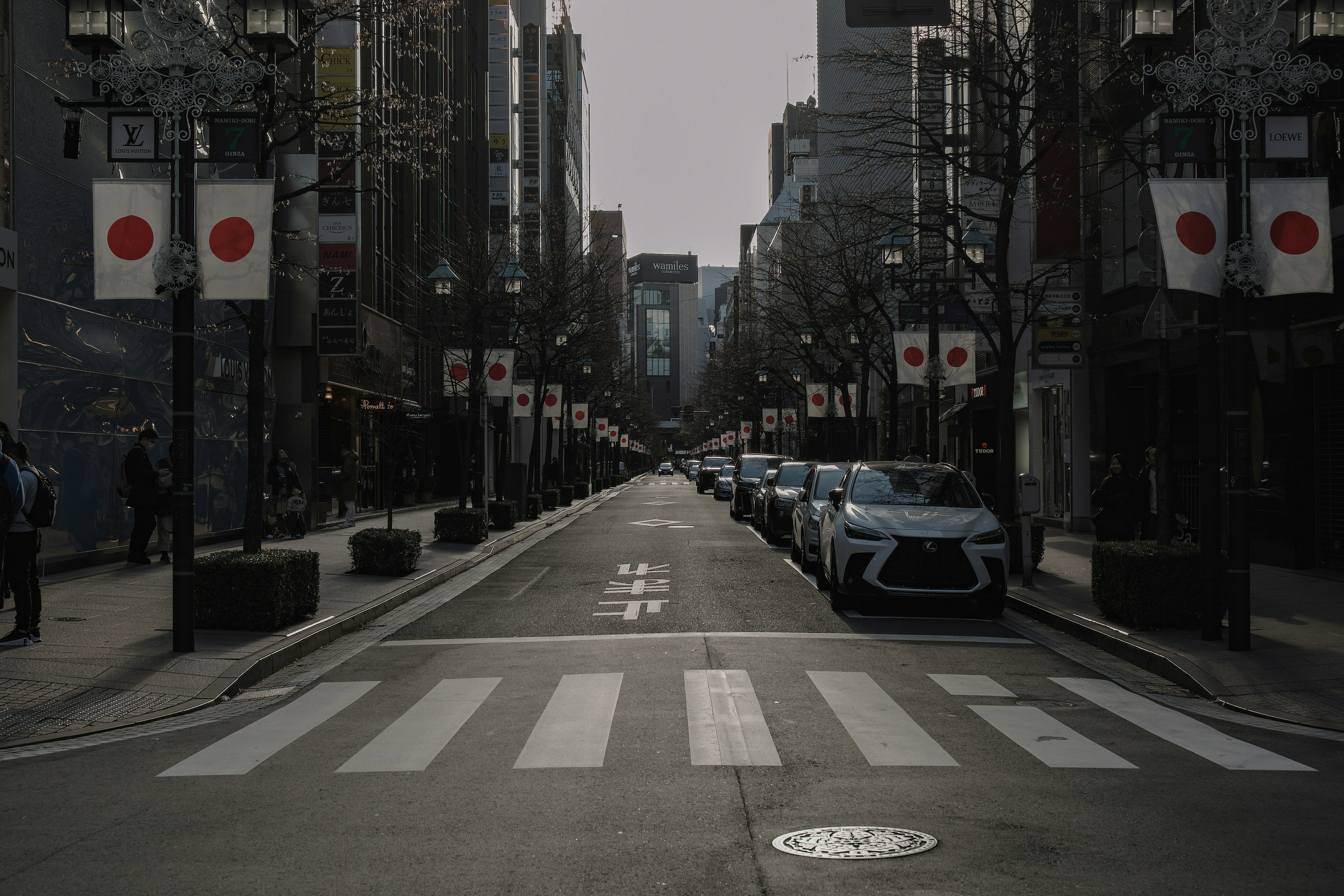 Jalan tenang dipenuhi bendera Jepang dan mobil terparkir