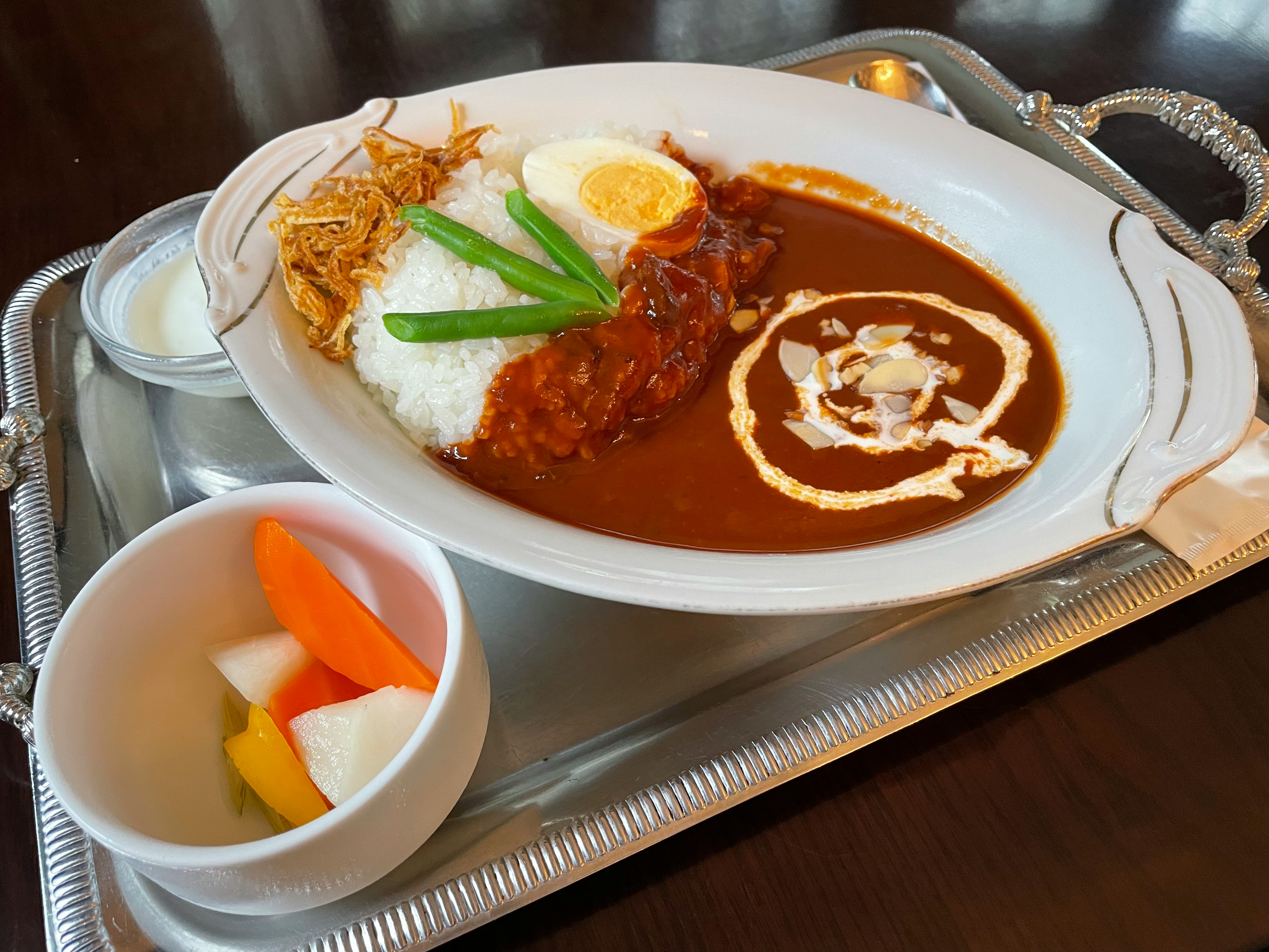 Curry rice with vegetables and side fruit served on a tray