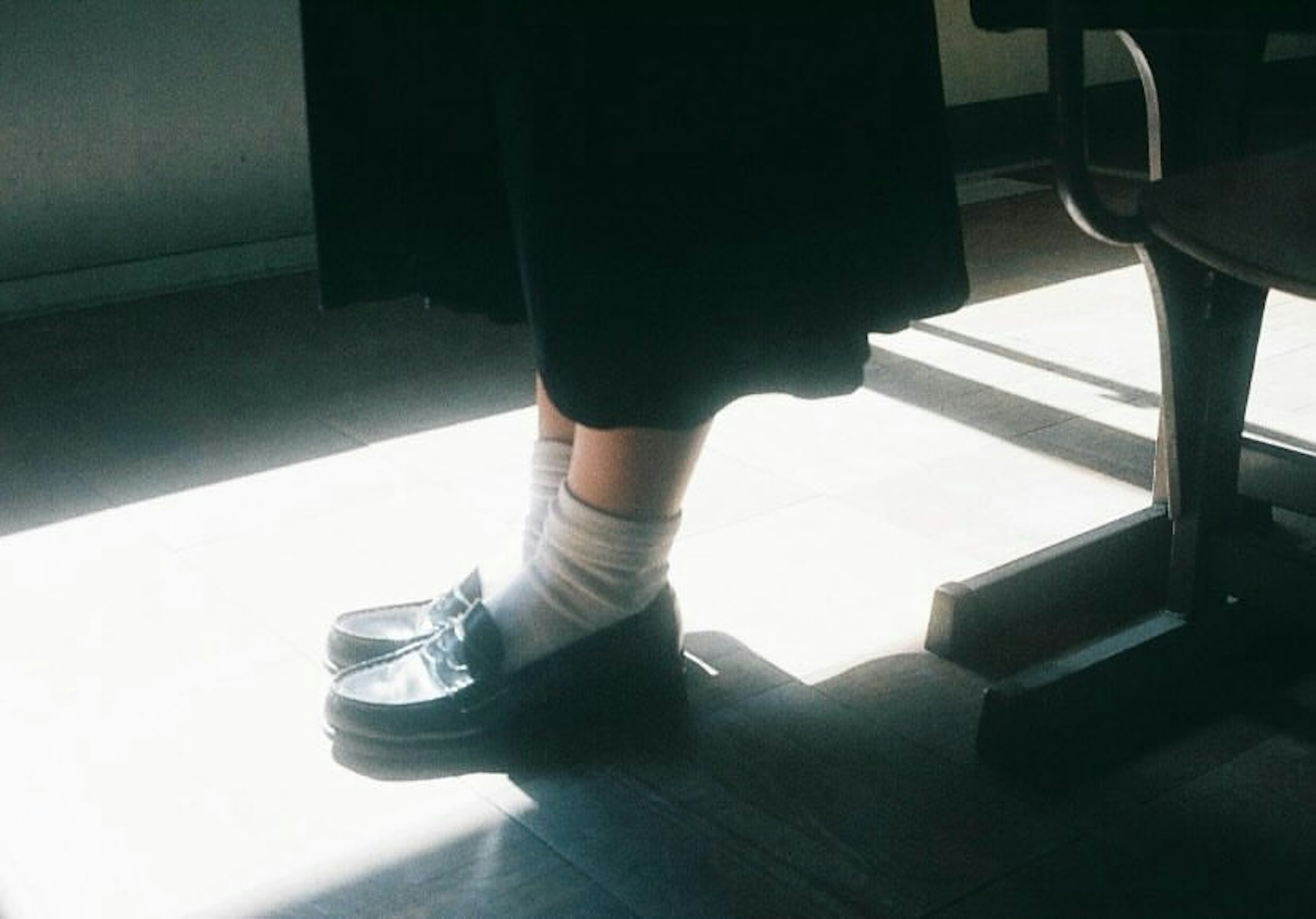 Glänzende schwarze Schuhe und weiße Socken in einem sonnigen Raum