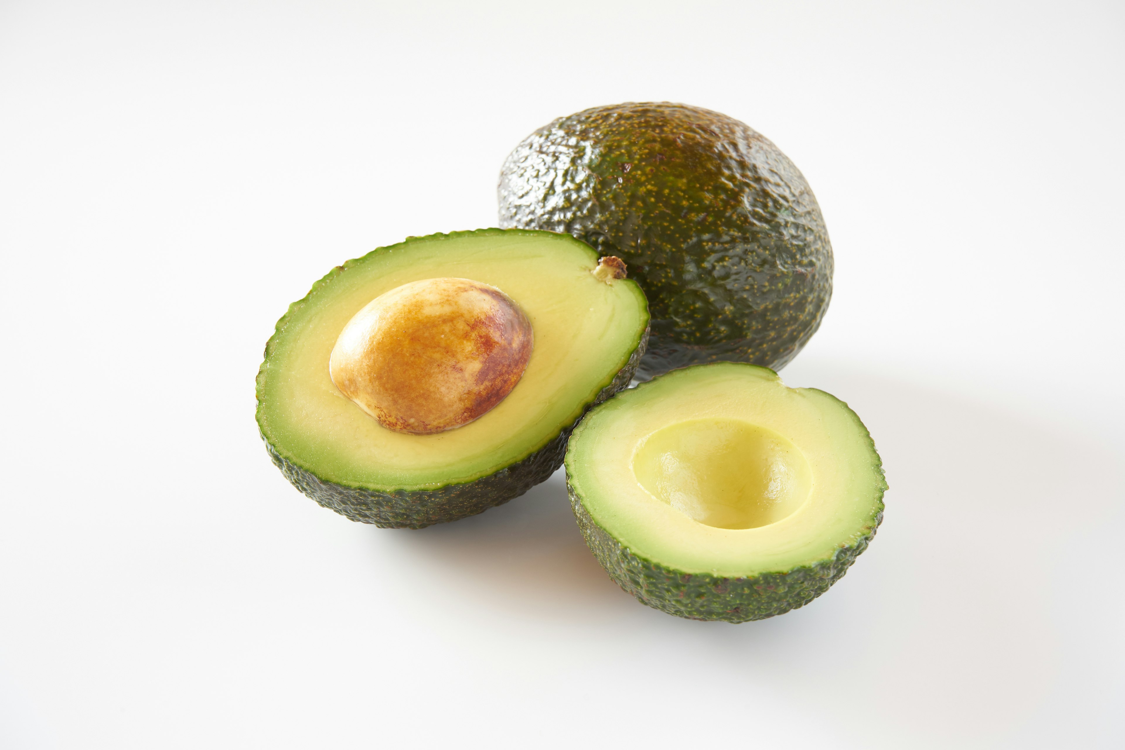 Immagine di avocado interi e tagliati che mostrano la loro polpa verde e il nocciolo marrone