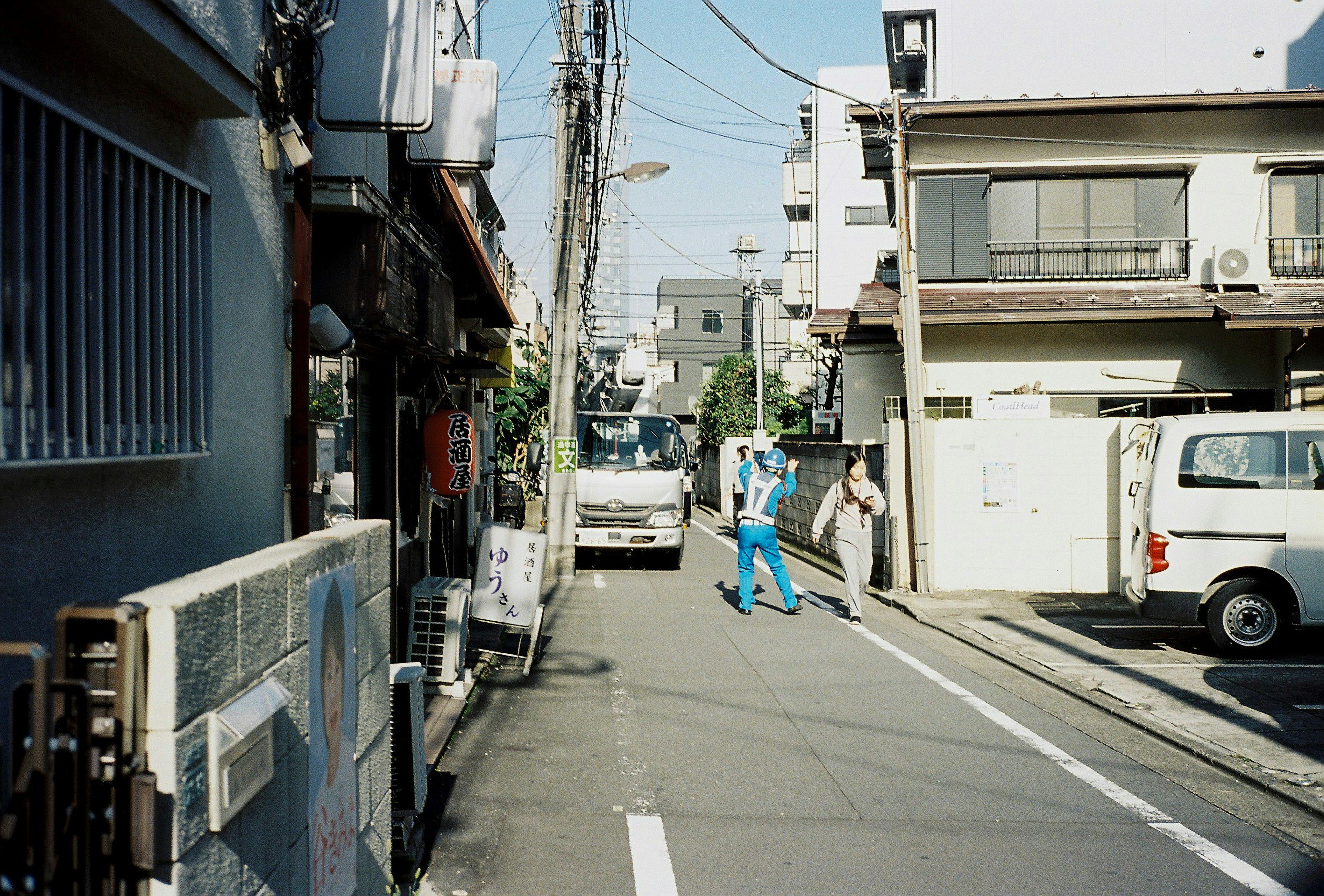 狭窄街道场景，住宅和商店，穿着蓝色工作服的人在走