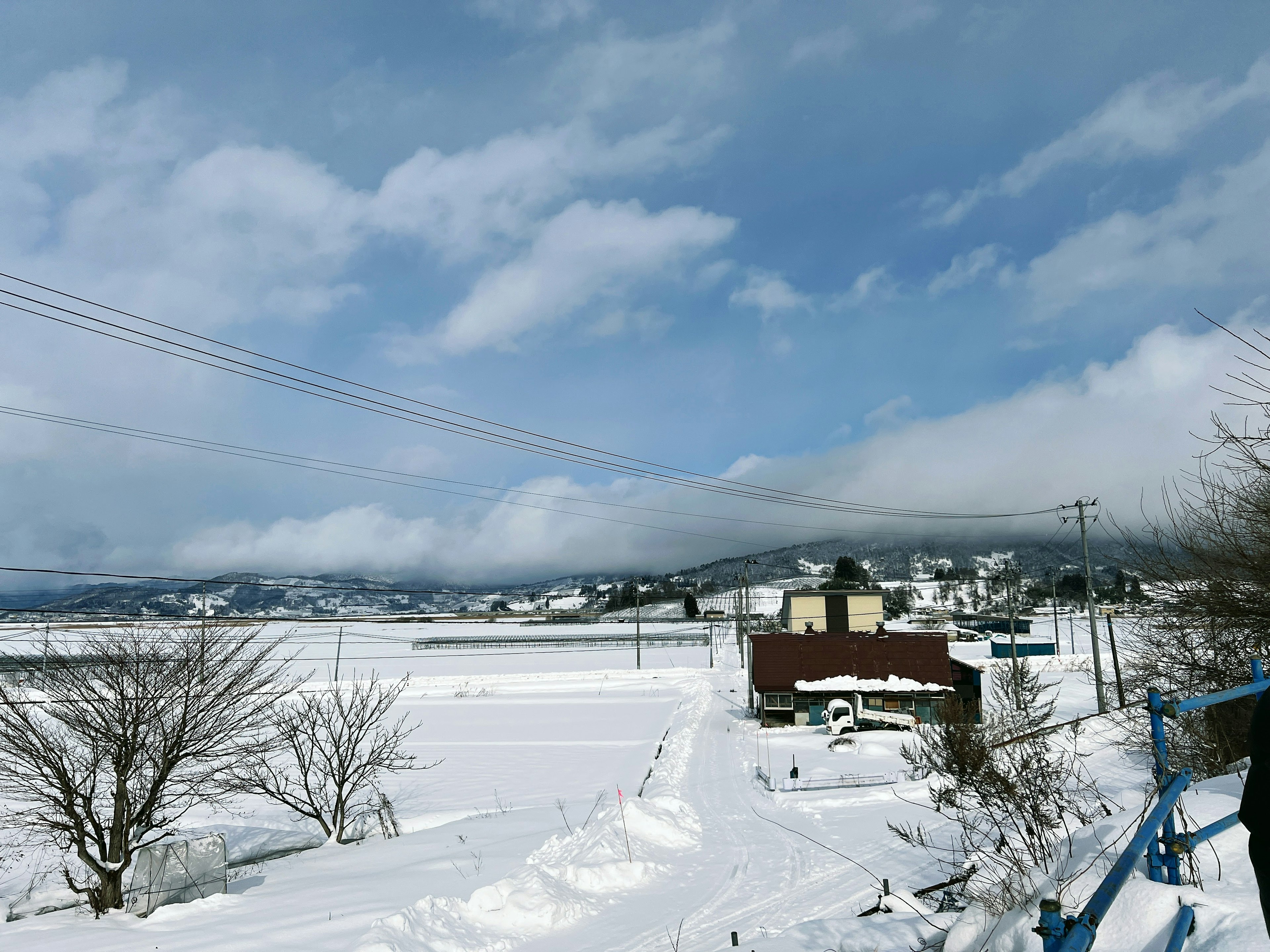 Snow-covered landscape with a blue sky and clouds