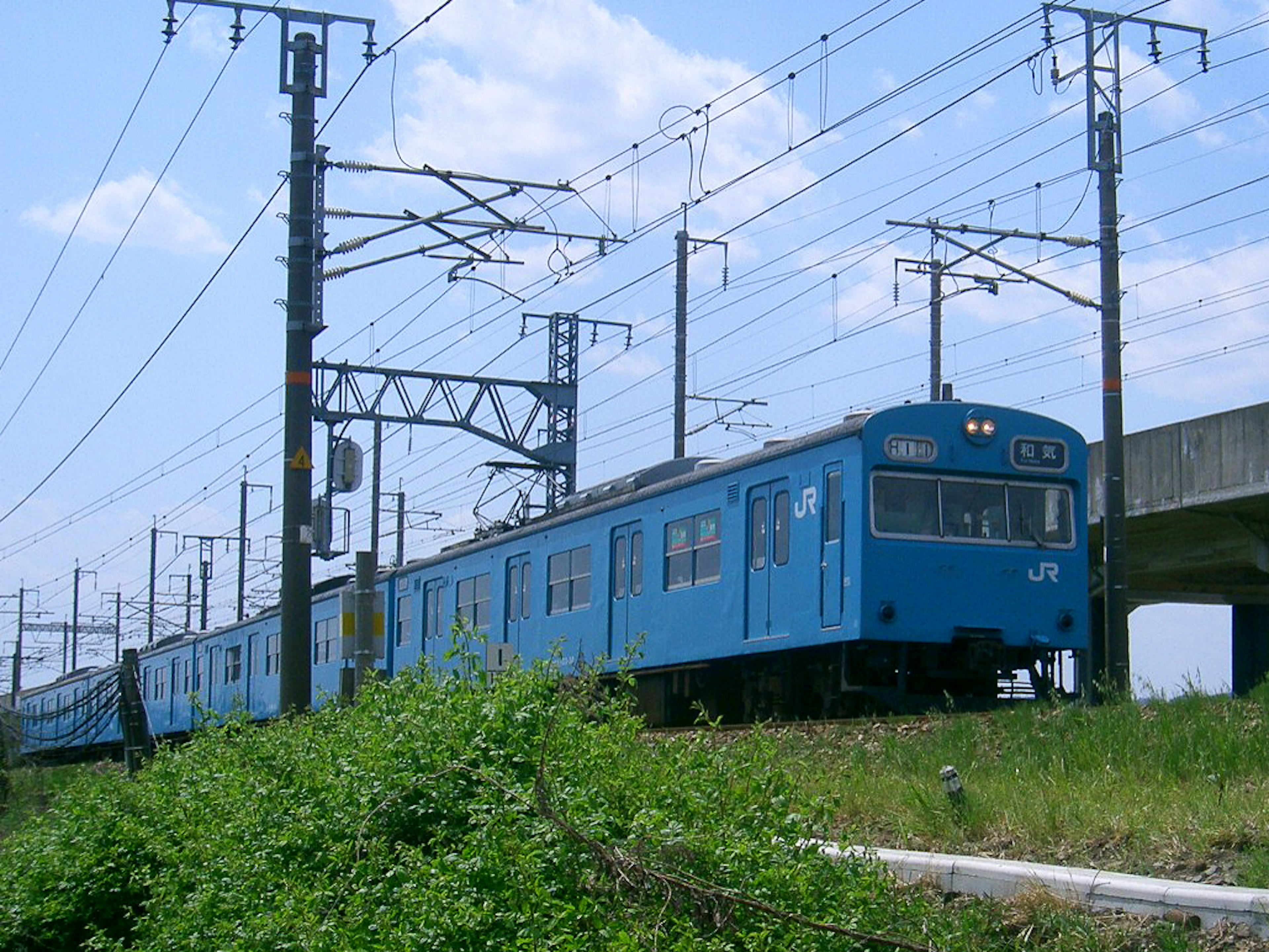 รถไฟสีน้ำเงินกำลังวิ่งอยู่บนรางใต้ท้องฟ้าที่แจ่มใส