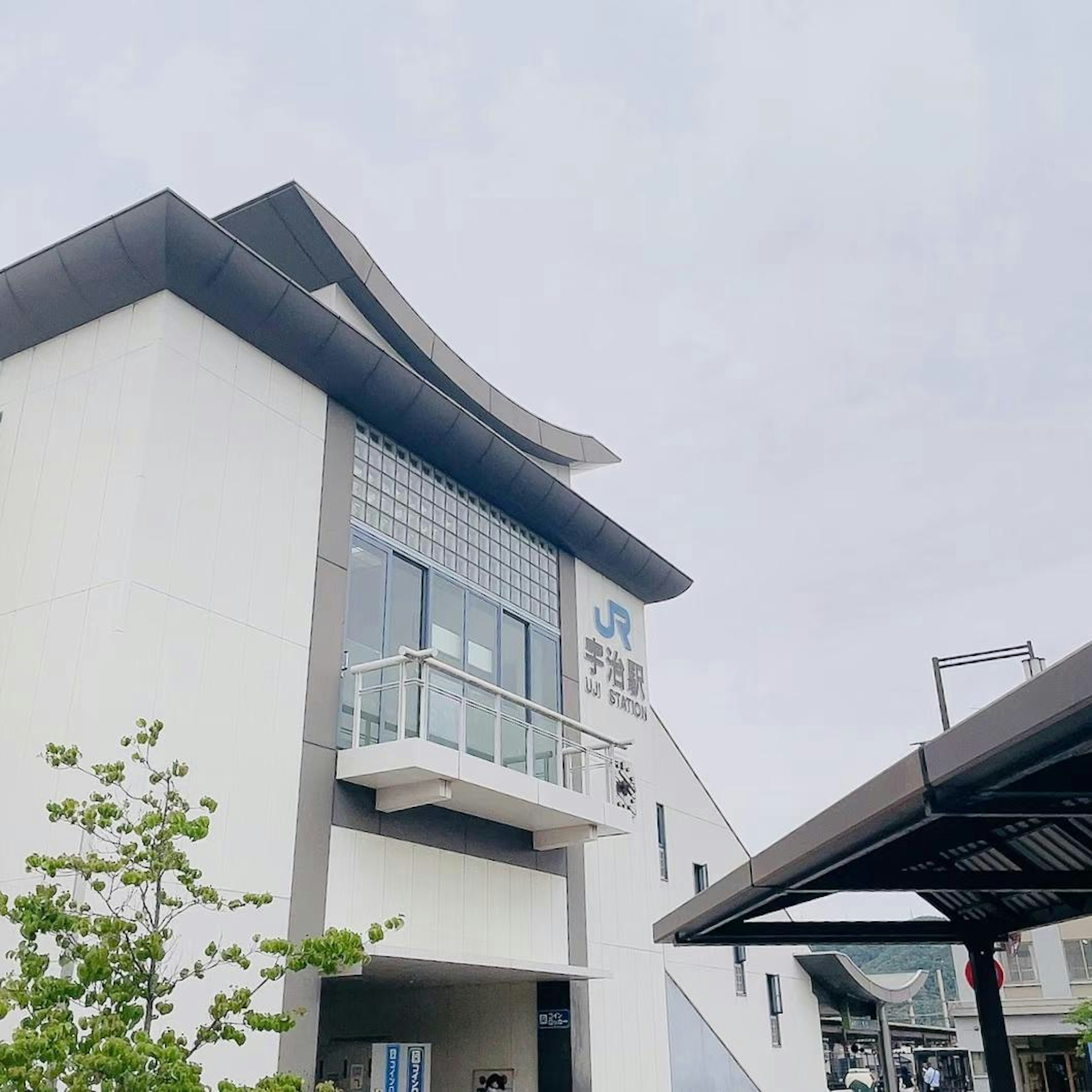 Train station building with white exterior and large windows green trees in front