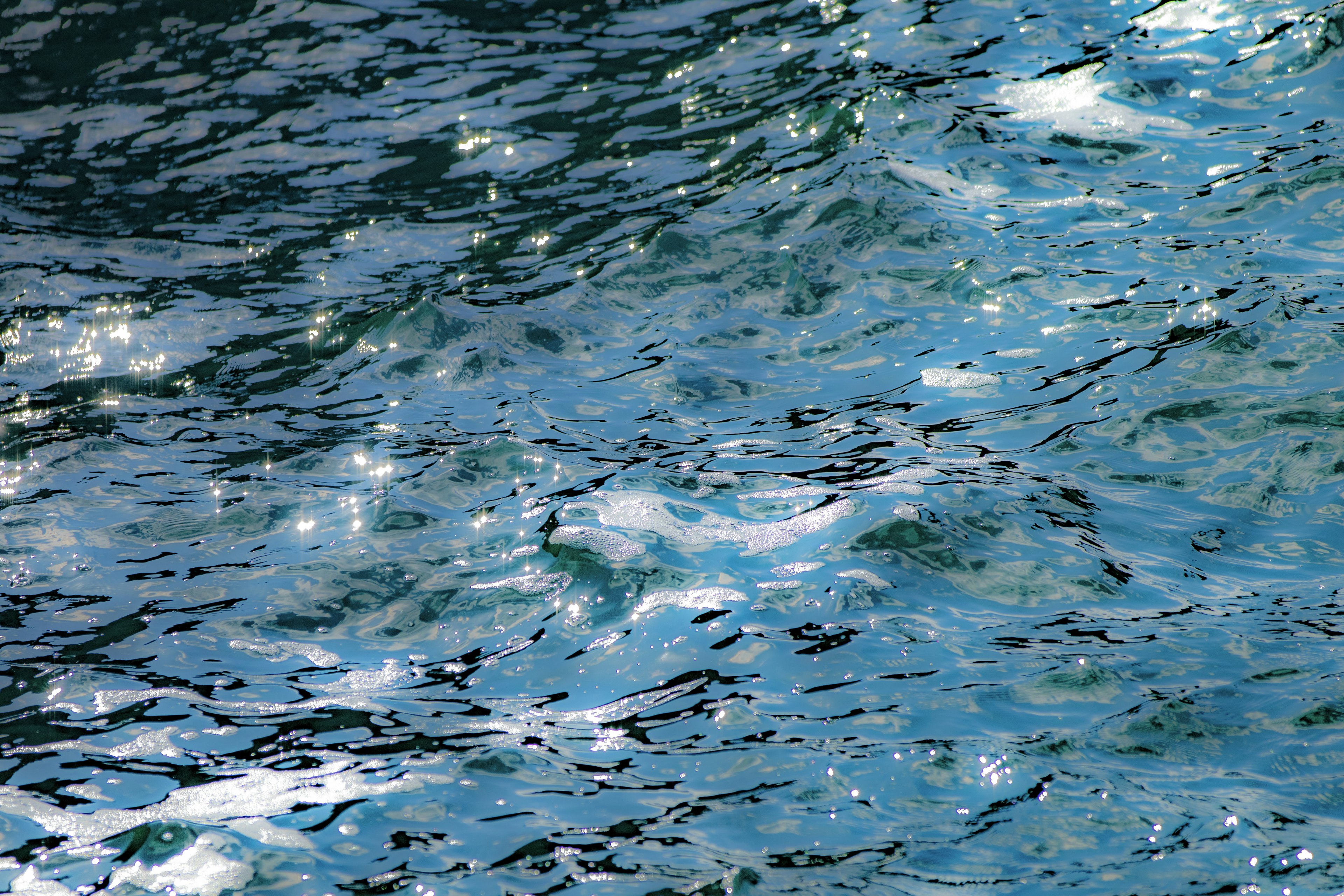 Surface d'eau bleue ondulante reflétant la lumière