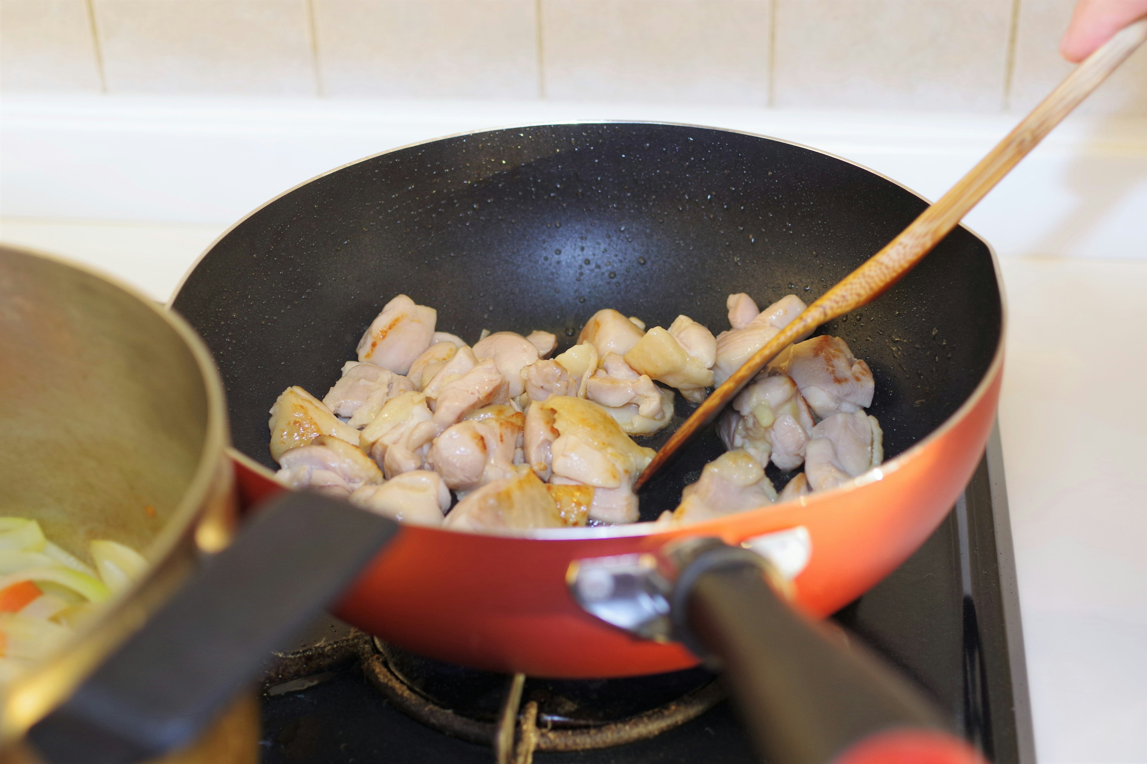 鍋で肉を炒めている様子 木製のスプーンを使っている