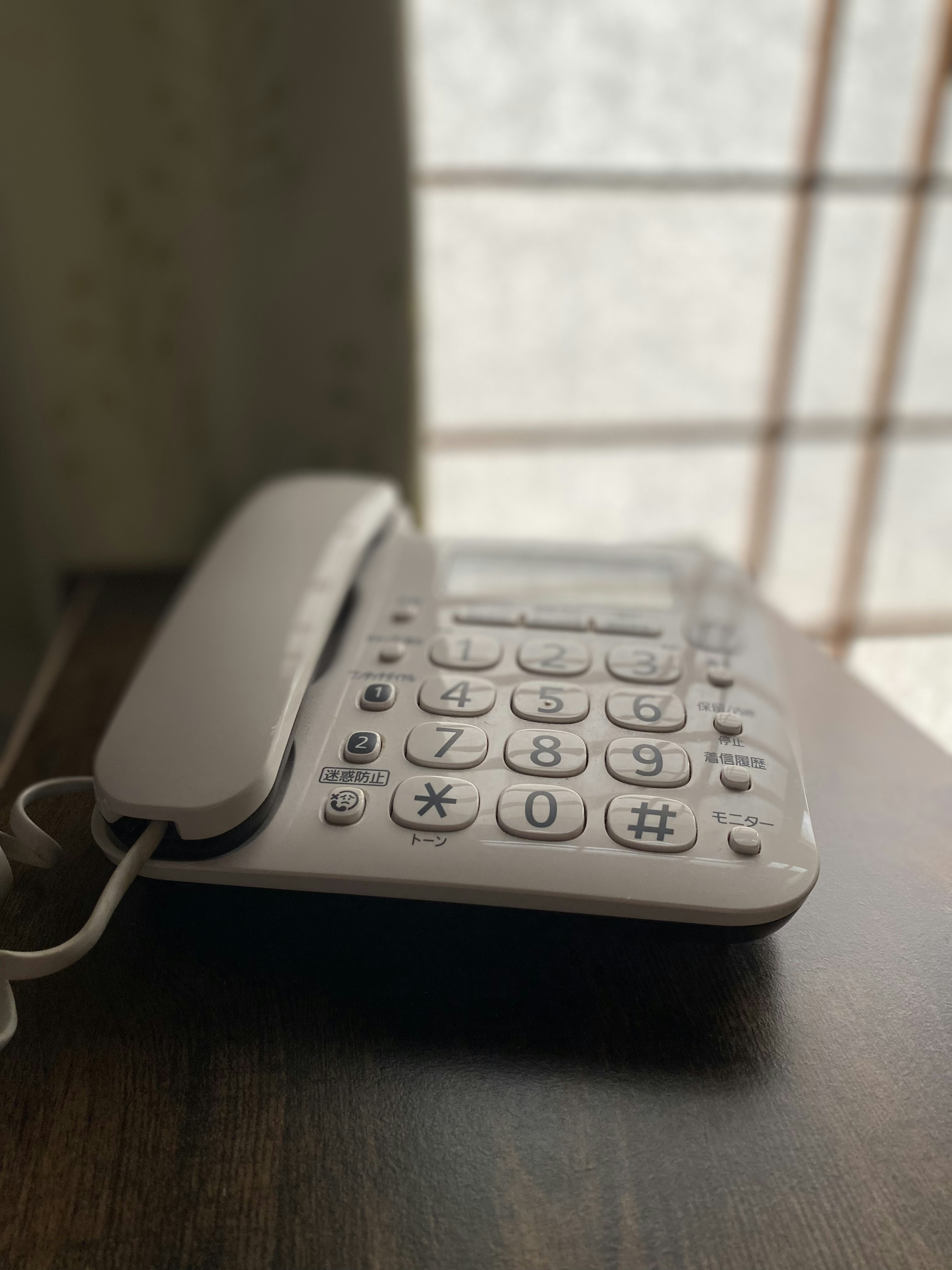 Un teléfono fijo blanco colocado sobre una mesa de madera