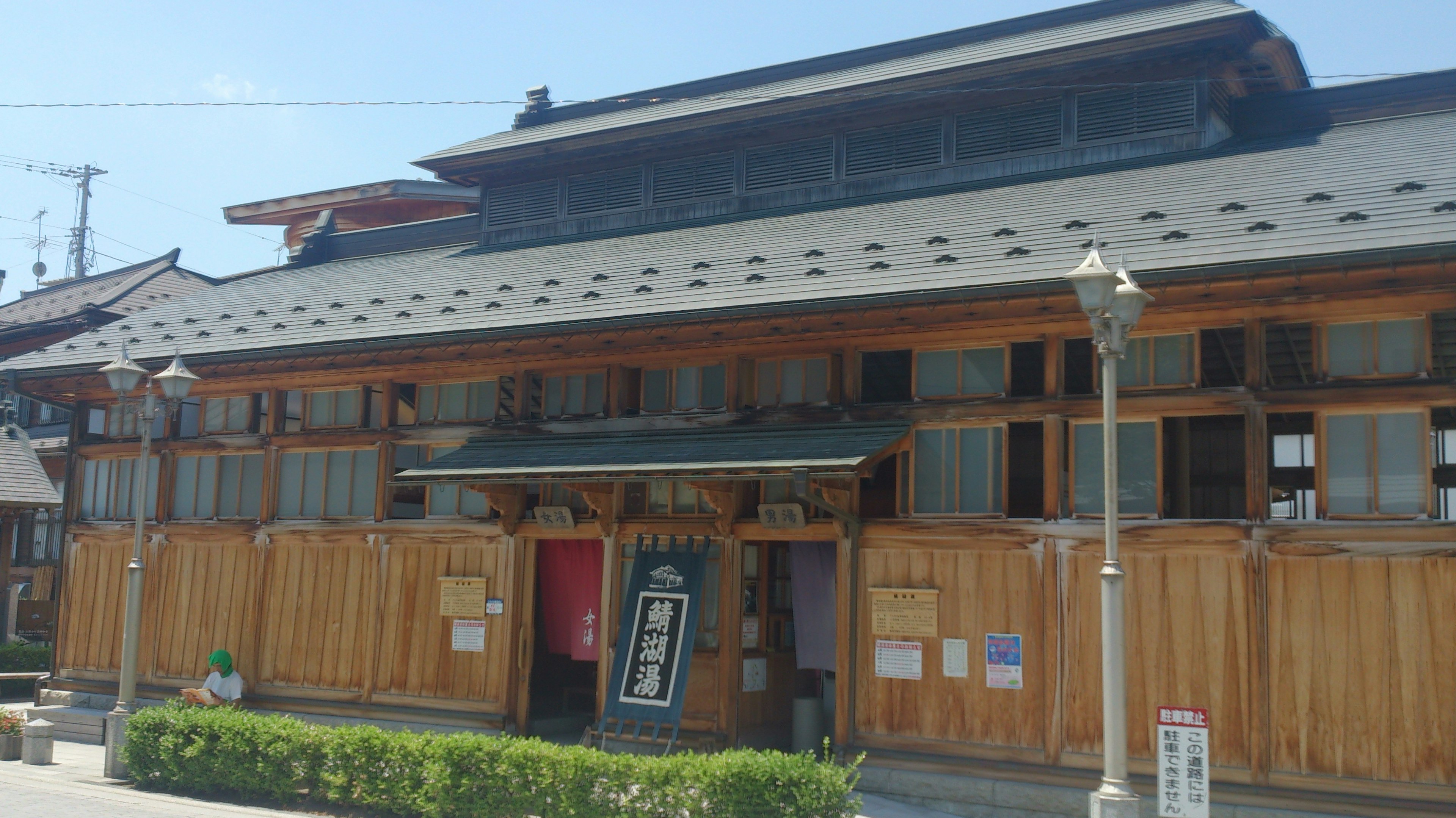 Exterior de un edificio japonés tradicional de madera con paisajismo verde y techo decorativo