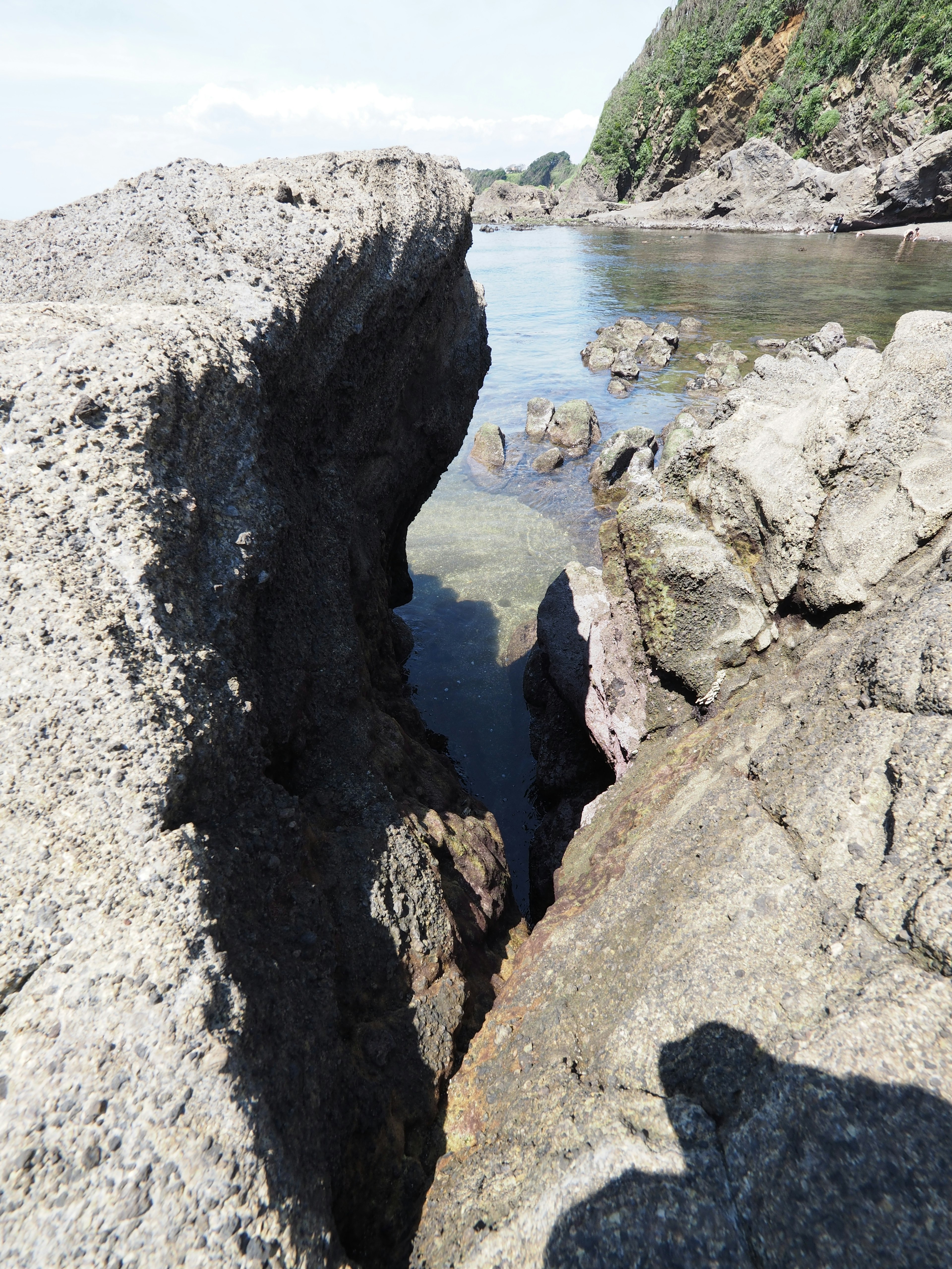 Eine enge Felsritze, die zu einem ruhigen Wasserbecken führt, umgeben von Natur