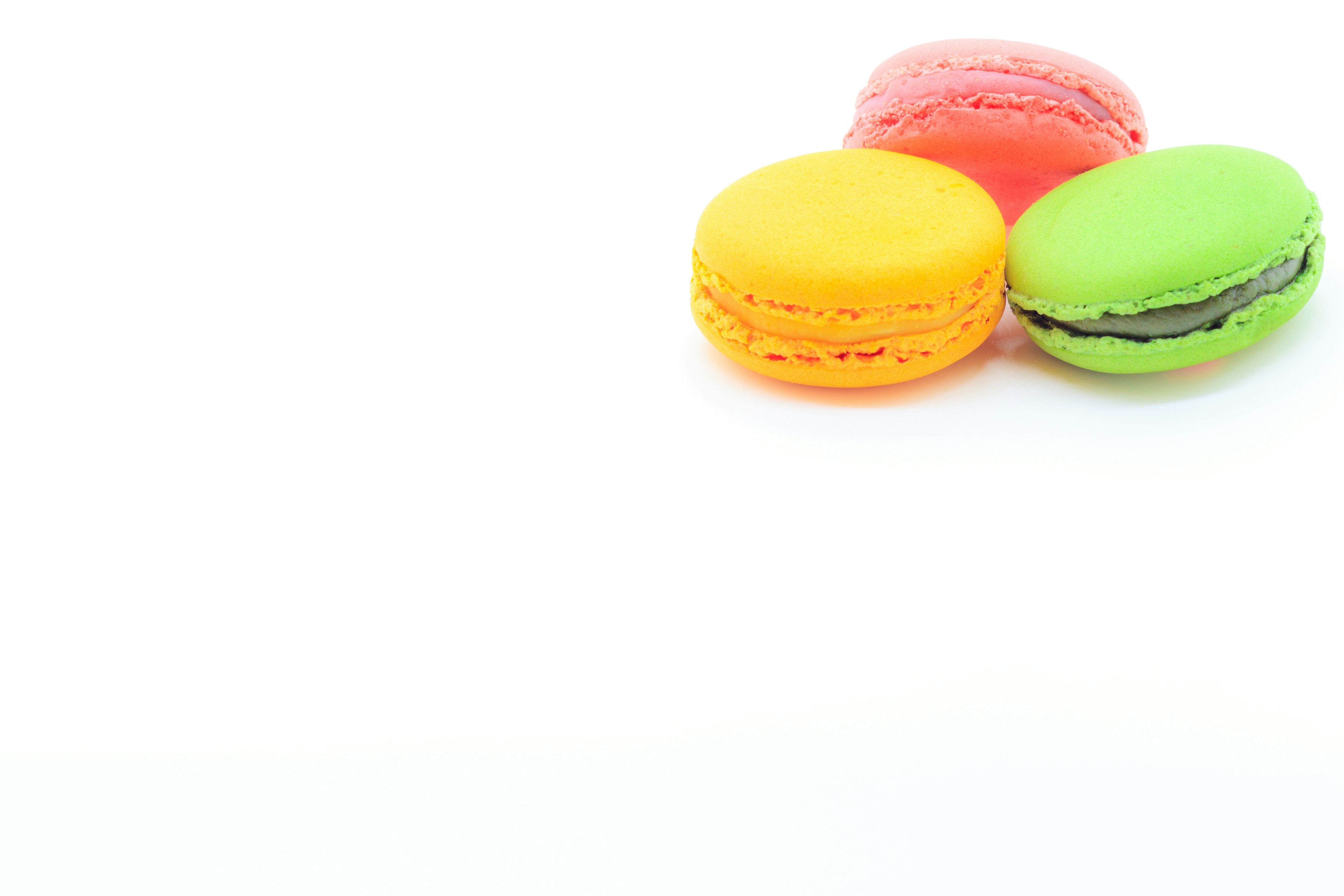 Hình ảnh macarons nhiều màu sắc với macarons đỏ, cam và xanh lá cây trên nền trắng