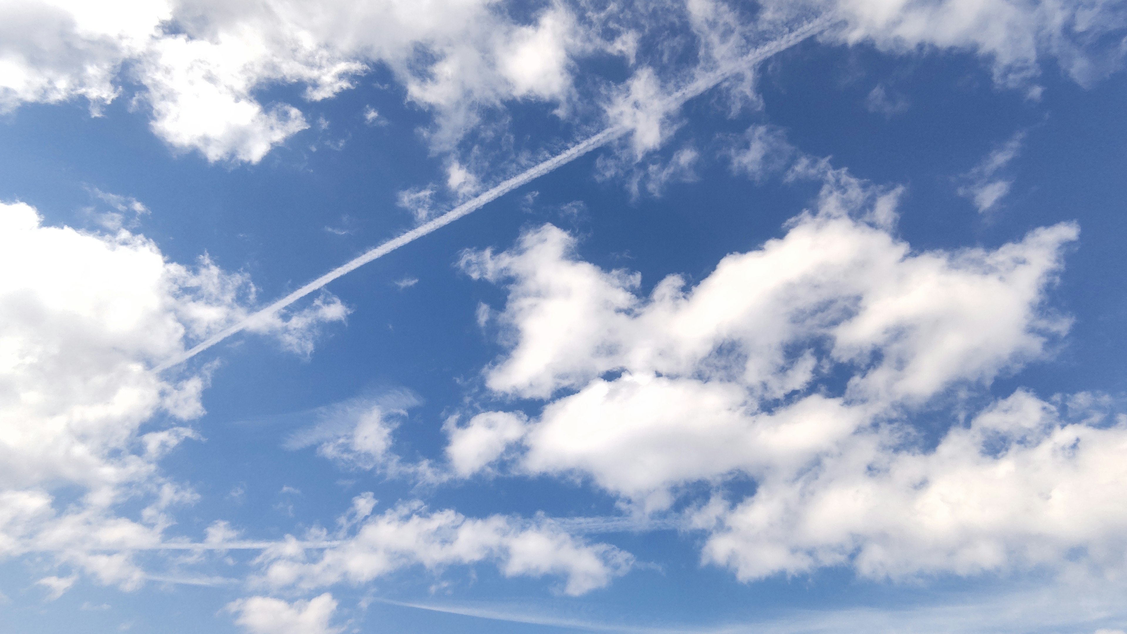 Weiße Wolken und Flugzeugstreifen in einem blauen Himmel