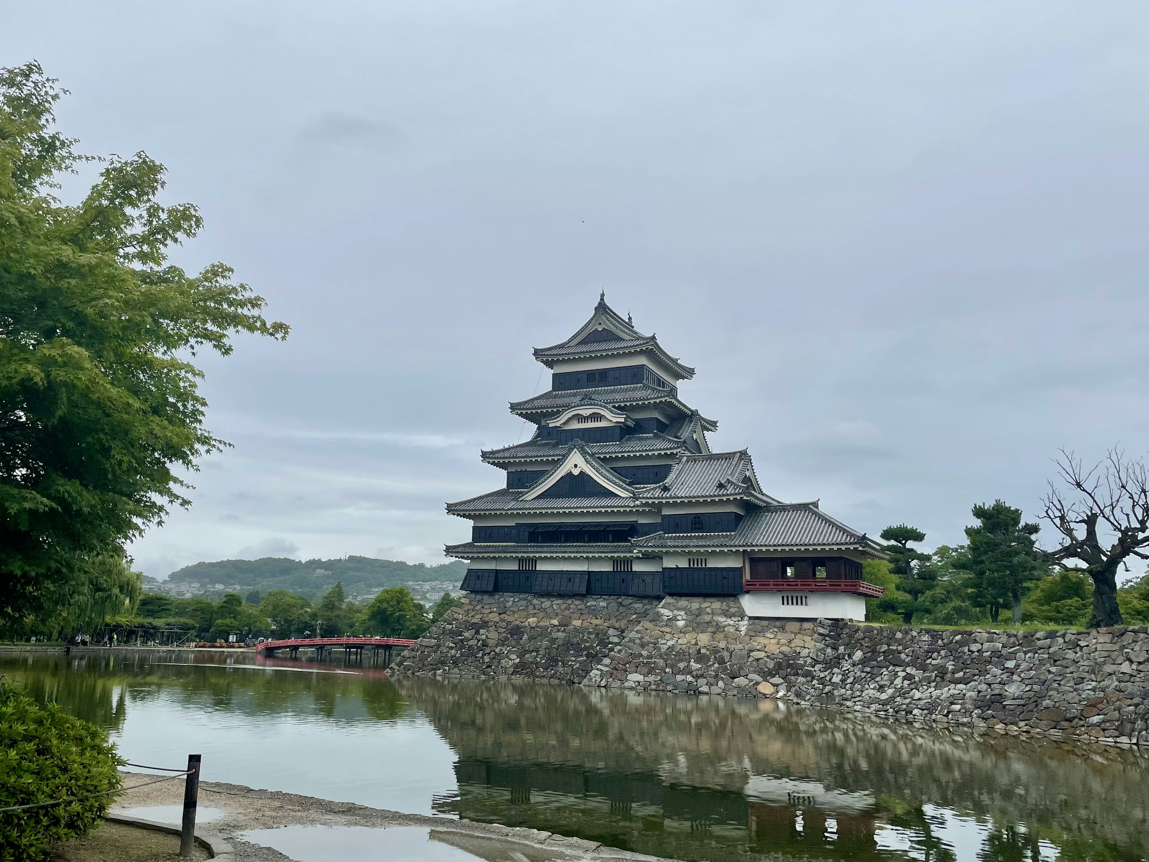 Vista del castillo de Matsumoto con una estructura negra reflejándose en el estanque adyacente