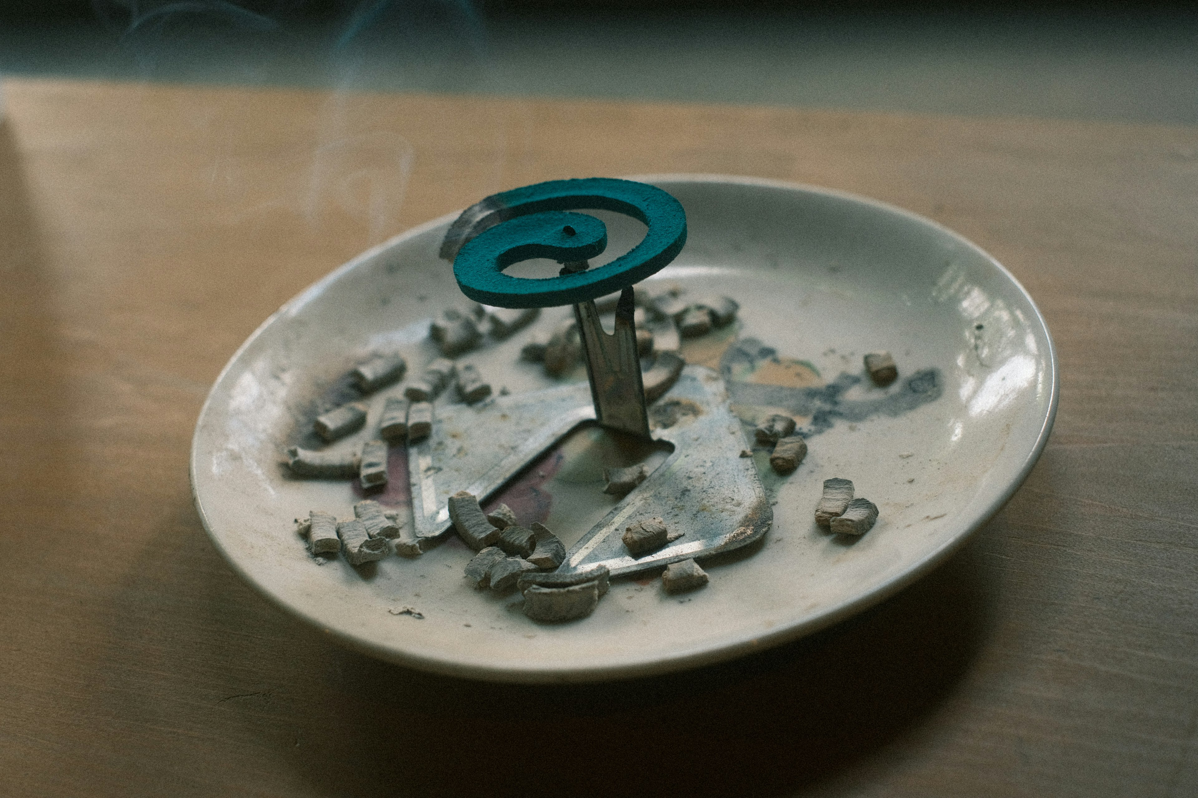 Blue ashtray with smoking remnants and scattered ash