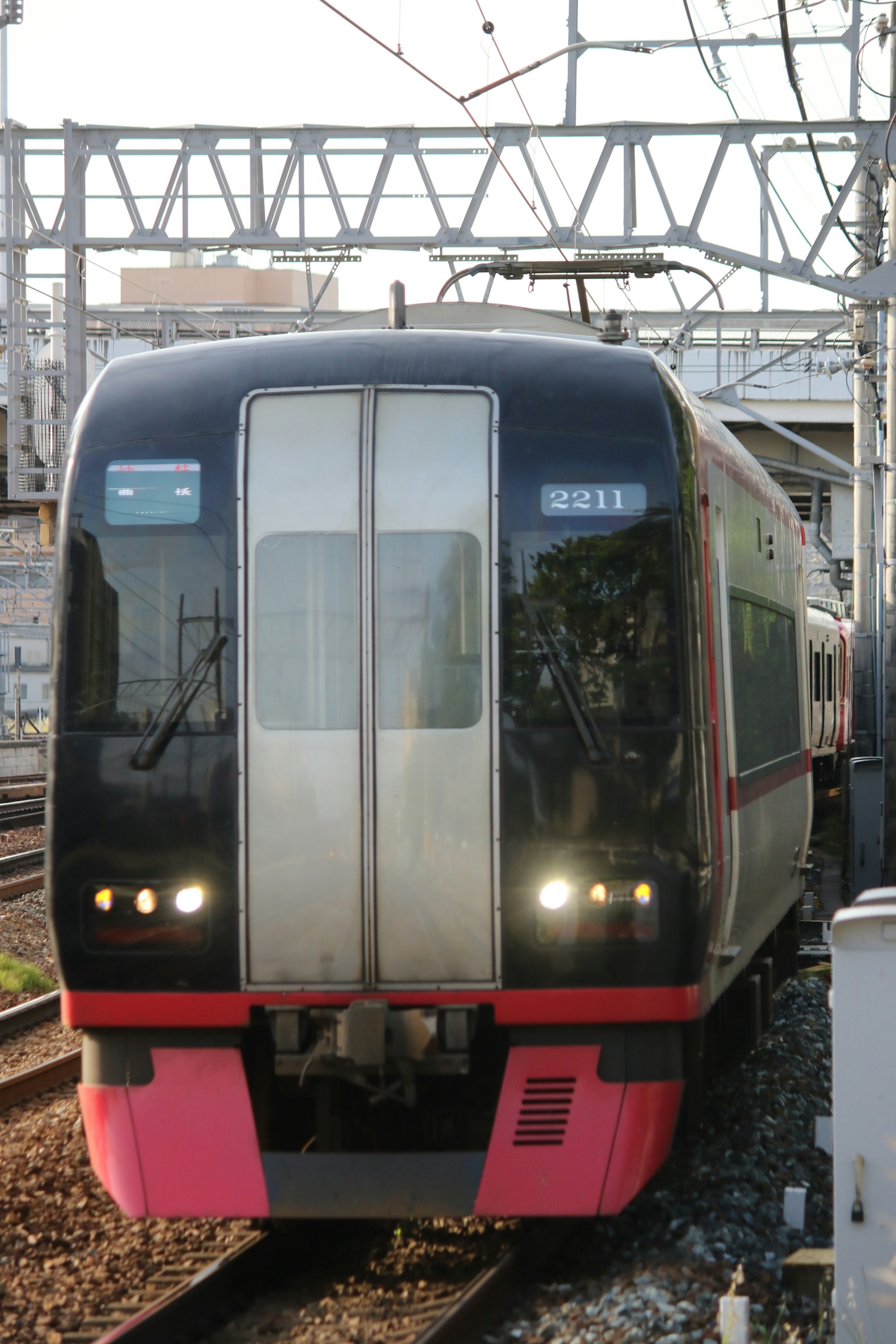 黒とピンクのデザインの電車が線路を走る