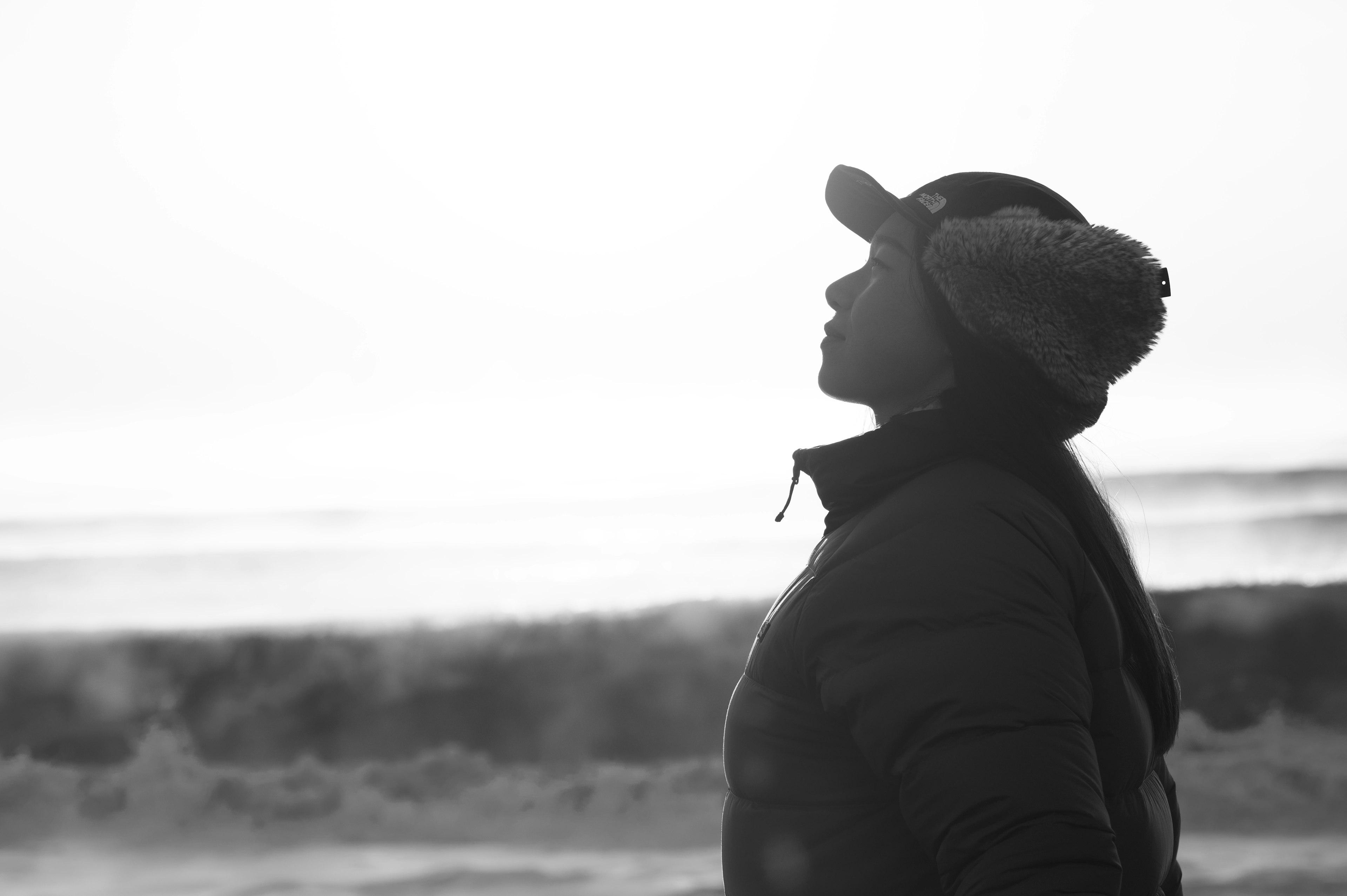 Silhouette of a person looking up at the sky by the beach